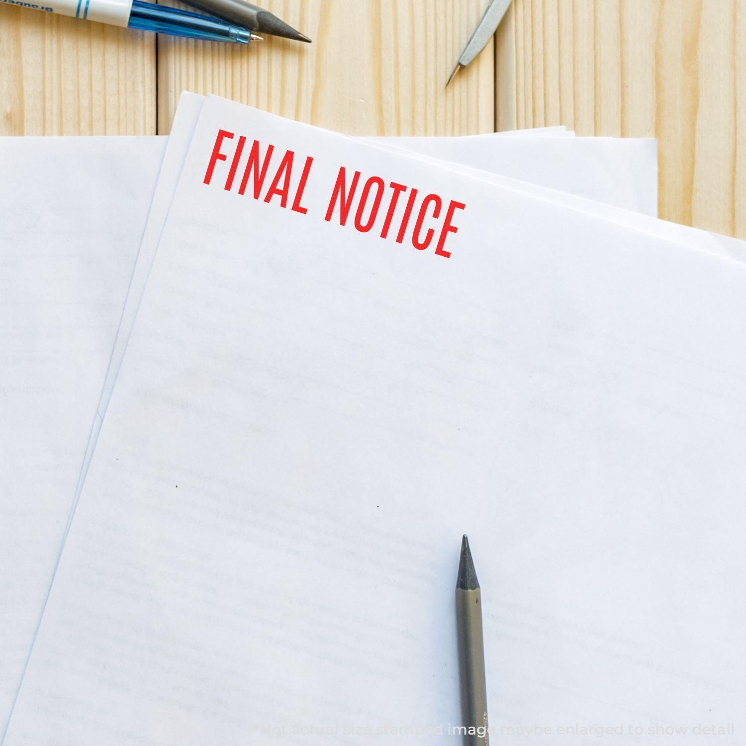 Large Self Inking Narrow Font Final Notice Stamp in red ink on a stack of white papers, with pens and a wooden desk in the background.