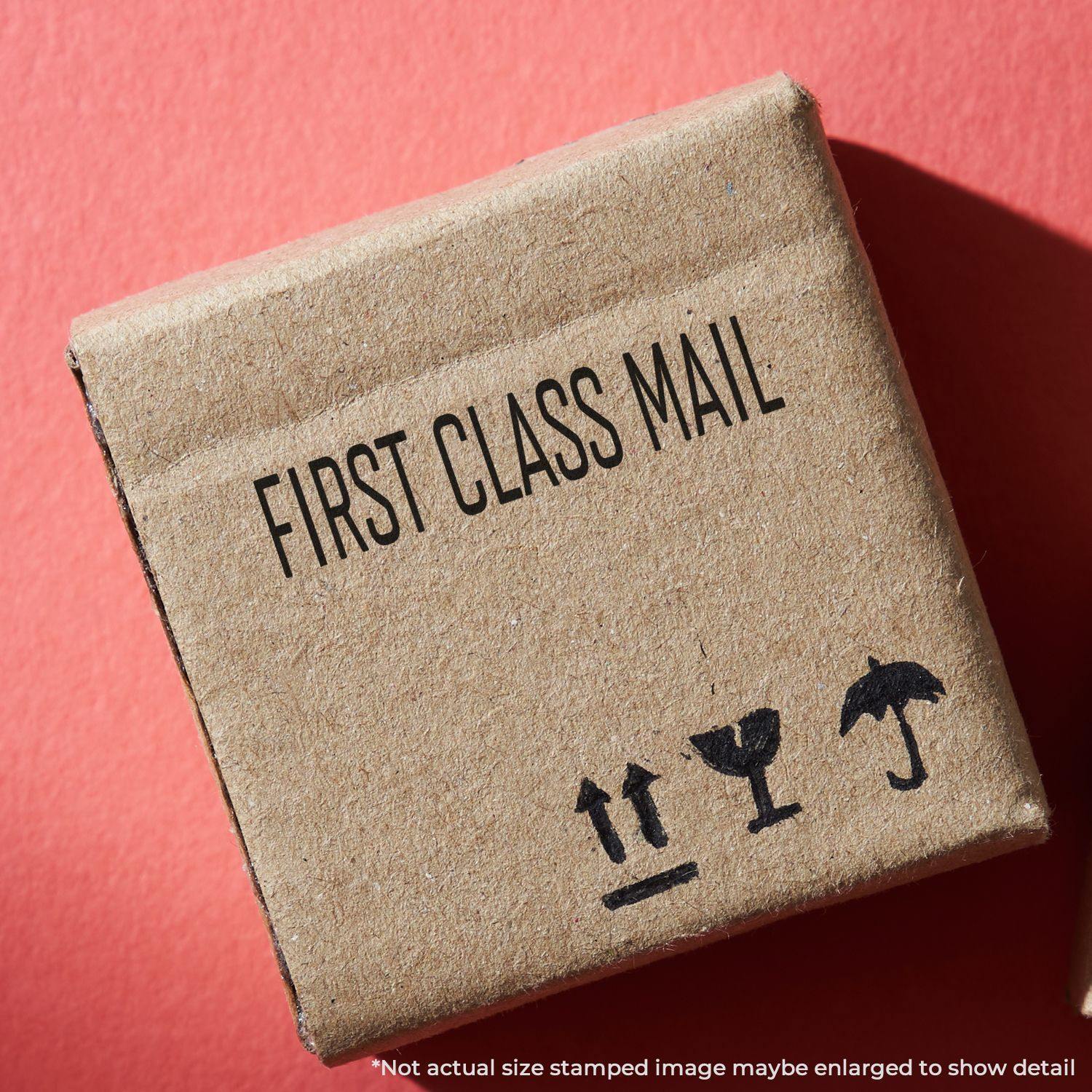 A cardboard box stamped with FIRST CLASS MAIL using the Large Self Inking Narrow Font First Class Mail Stamp on a red background.