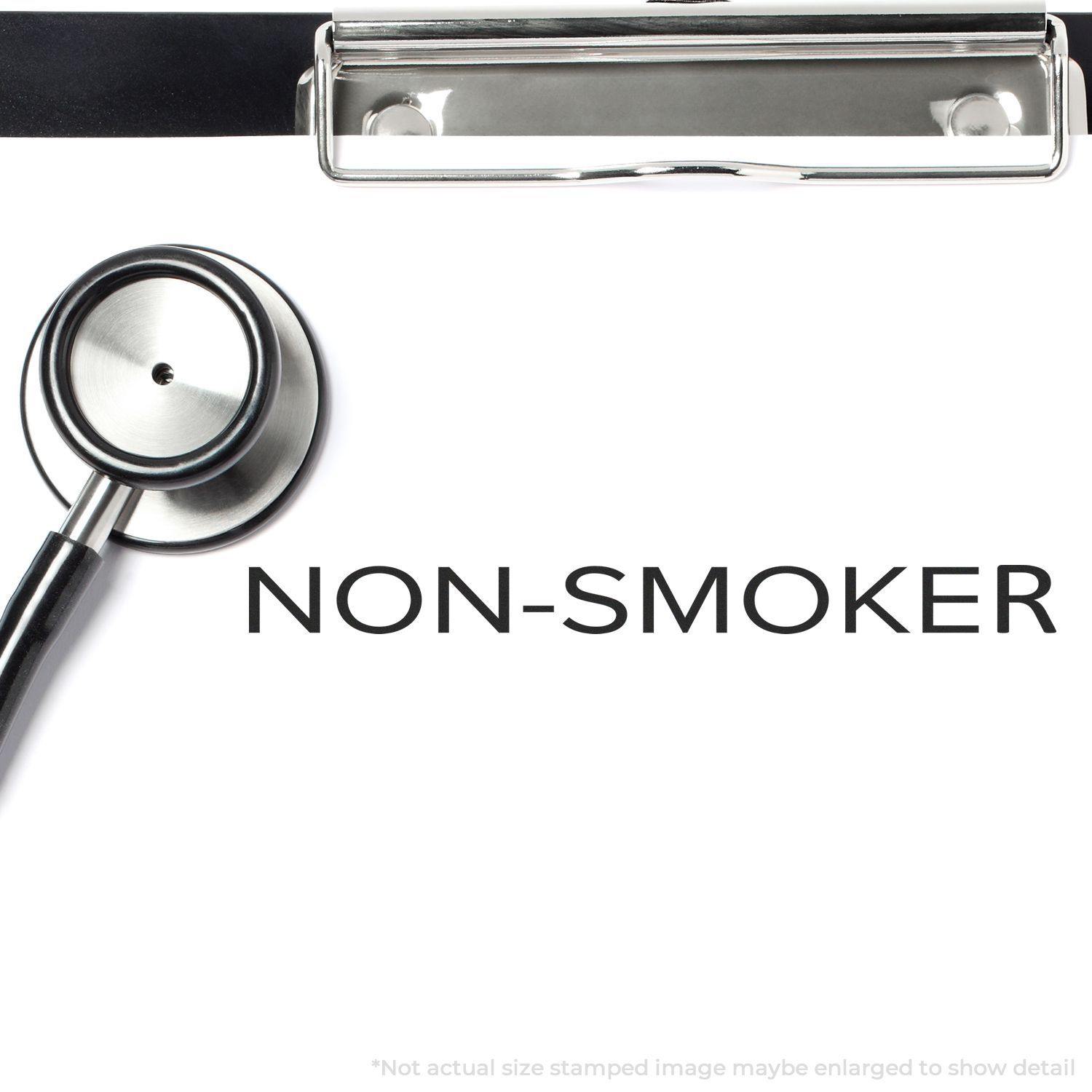 Slim Pre-Inked Narrow Font Non-Smoker Stamp on a white paper with a stethoscope and clipboard in the background.