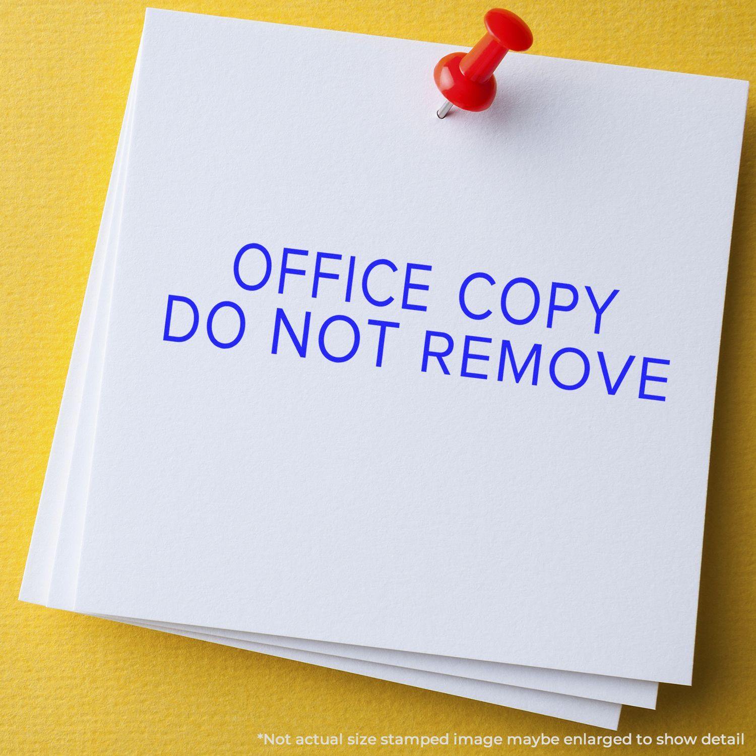 Large Narrow Font Office Copy Do Not Remove Rubber Stamp used on white paper pinned with a red pushpin on a yellow background.