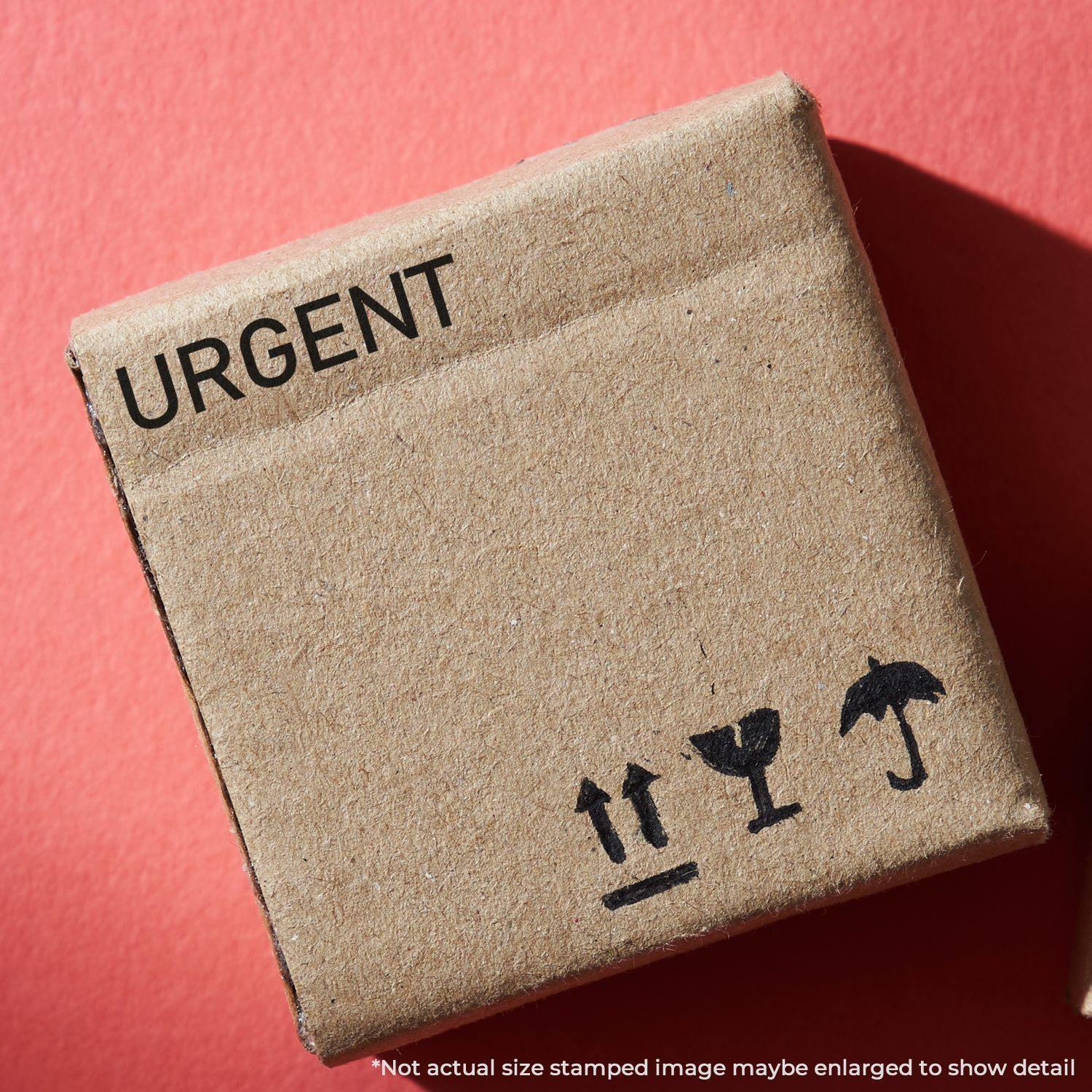 A cardboard box stamped with URGENT using a Slim Pre-Inked Narrow Font Urgent Stamp, placed on a red background.