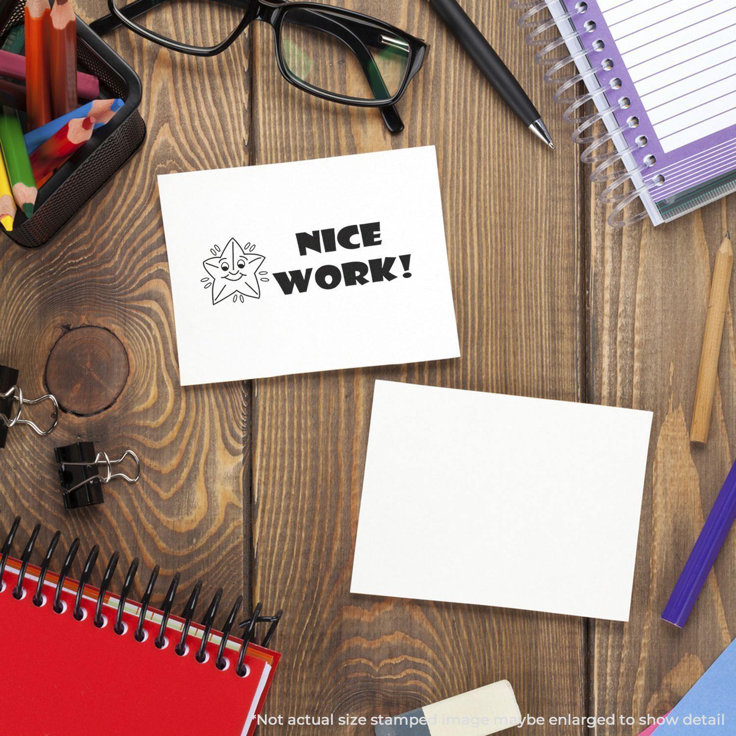 Large Self Inking Nice Work Stamp on a white card, surrounded by office supplies including notebooks, glasses, and pens on a wooden desk.