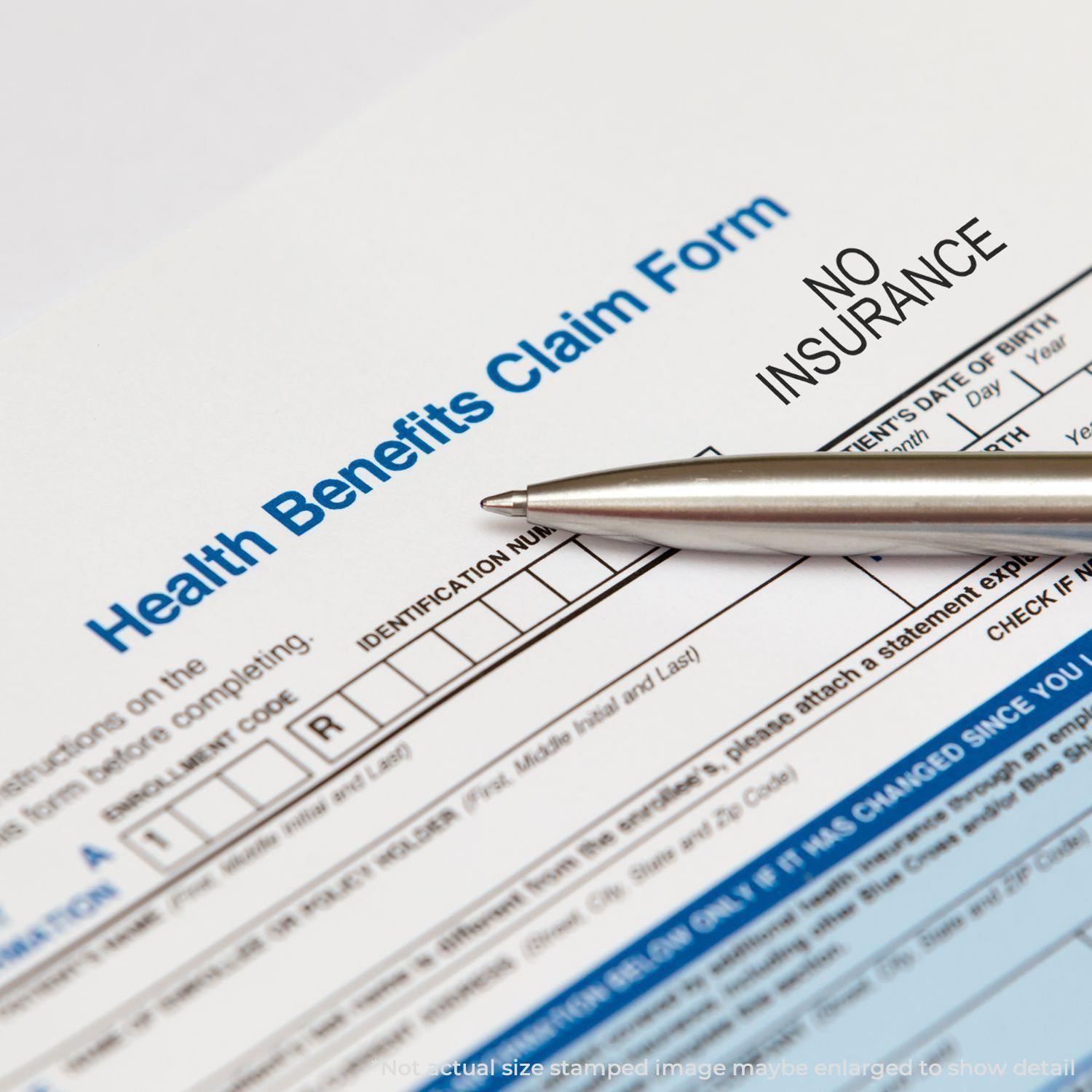 A Health Benefits Claim Form stamped with NO INSURANCE using the Large No Insurance Rubber Stamp, with a pen placed on the form.