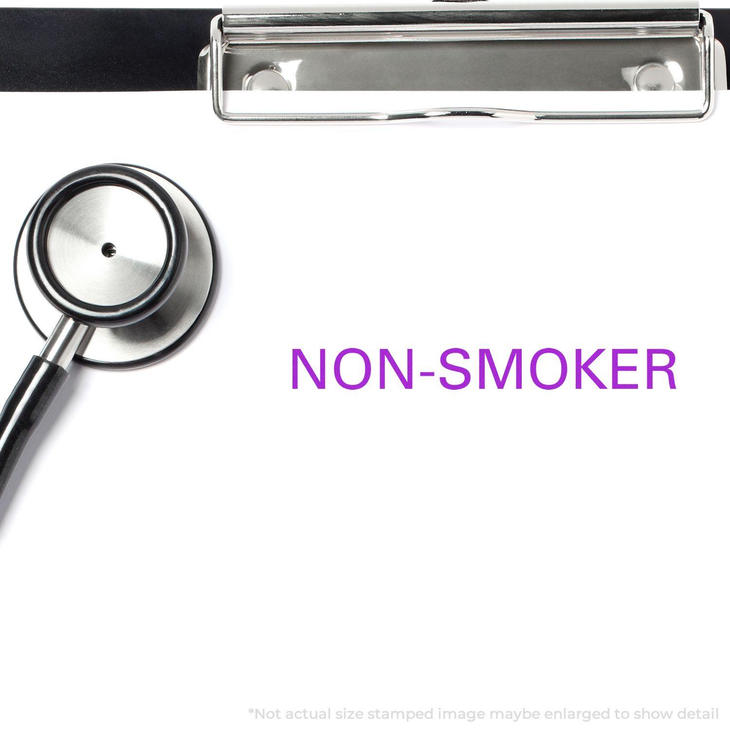 Large Pre-Inked Non-Smoker Stamp in use on a white paper with a stethoscope and clipboard nearby. The stamp reads NON-SMOKER in purple text.