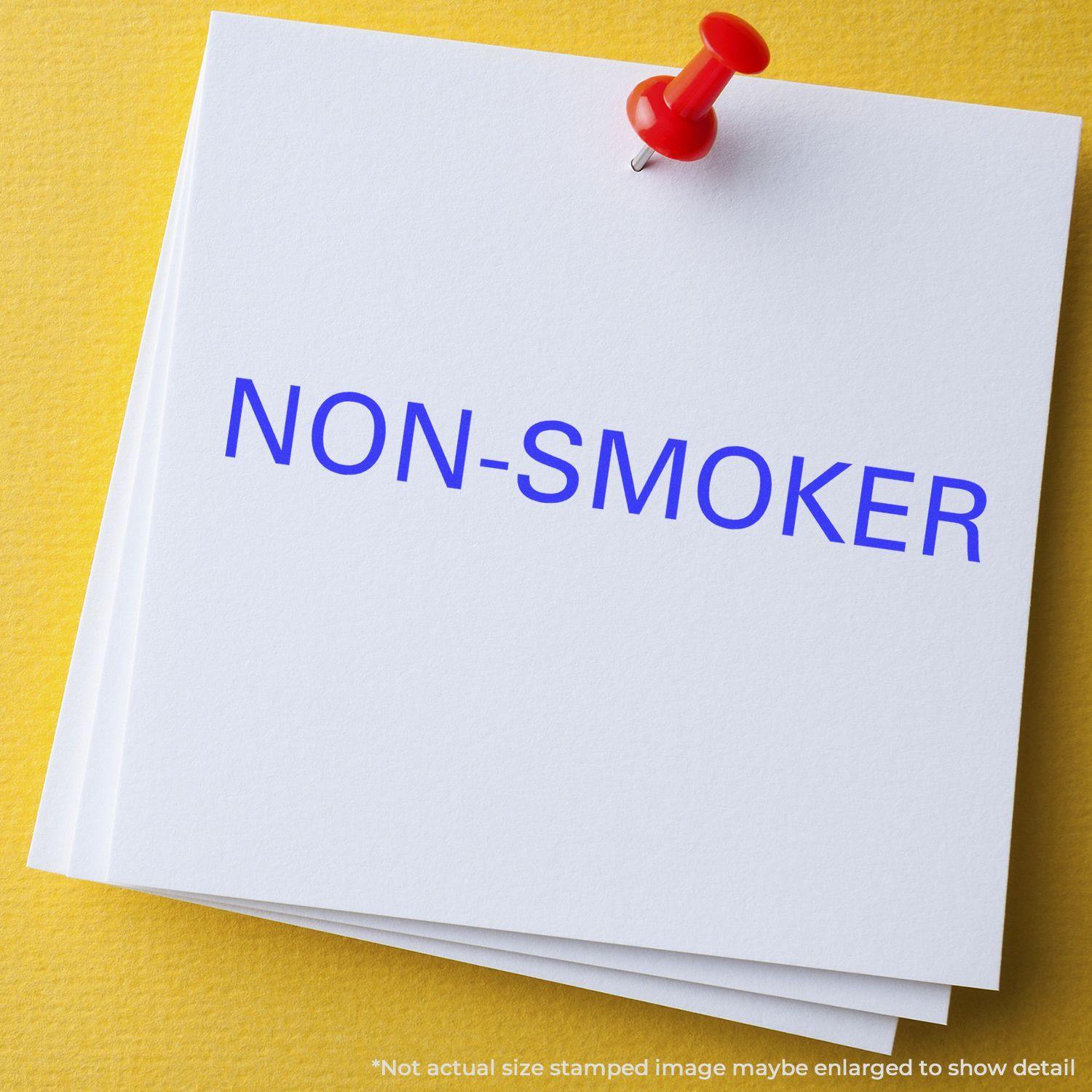 Slim Pre-Inked Non-Smoker Stamp used on white paper with a red pushpin on a yellow background.