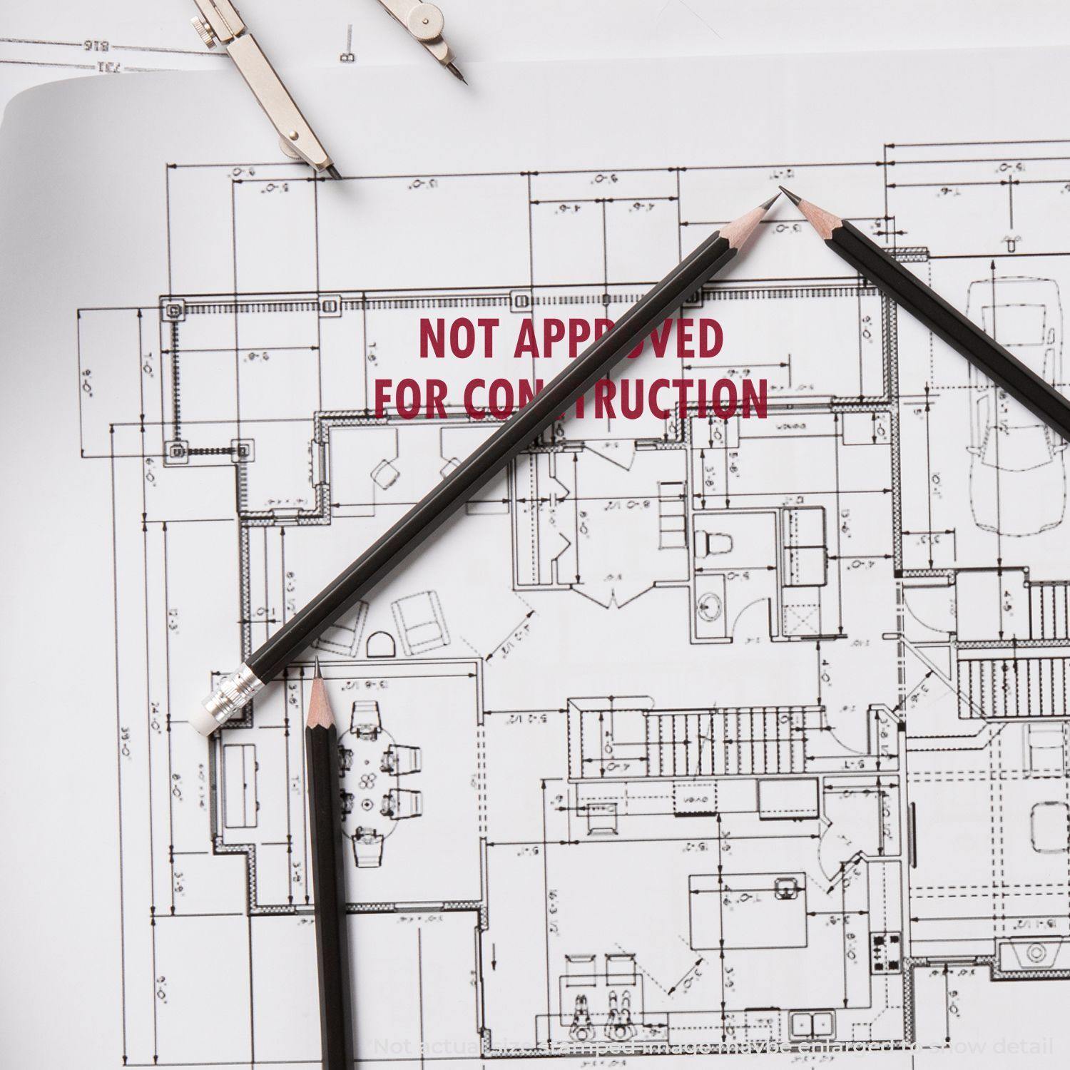 Large Not Approved For Construction Rubber Stamp on architectural blueprint with pencils and drafting tools.