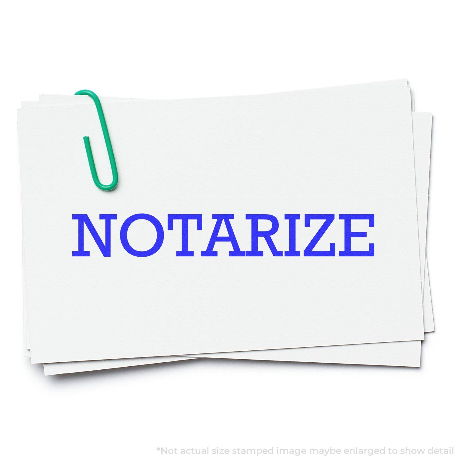 A stack of white papers with NOTARIZE stamped in blue ink using the Large Self Inking Notarize Stamp, held together by a green paperclip.