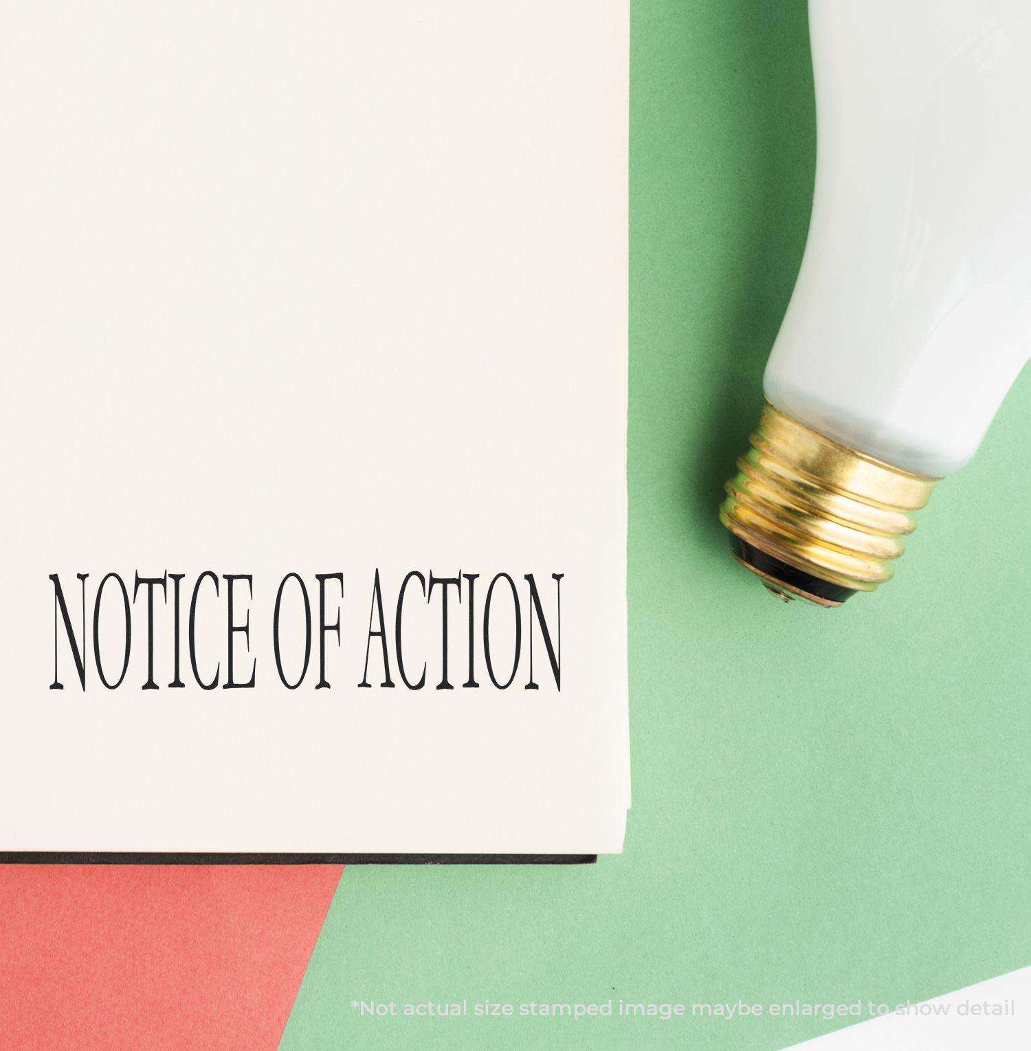 Large Pre-Inked Notice Of Action Stamp used on a document, with a light bulb and colored paper in the background.