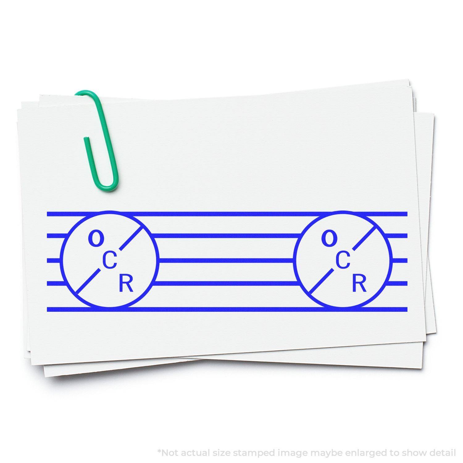 Large OCR Rubber Stamp in use, showing blue OCR design stamped on white cards with a green paperclip.