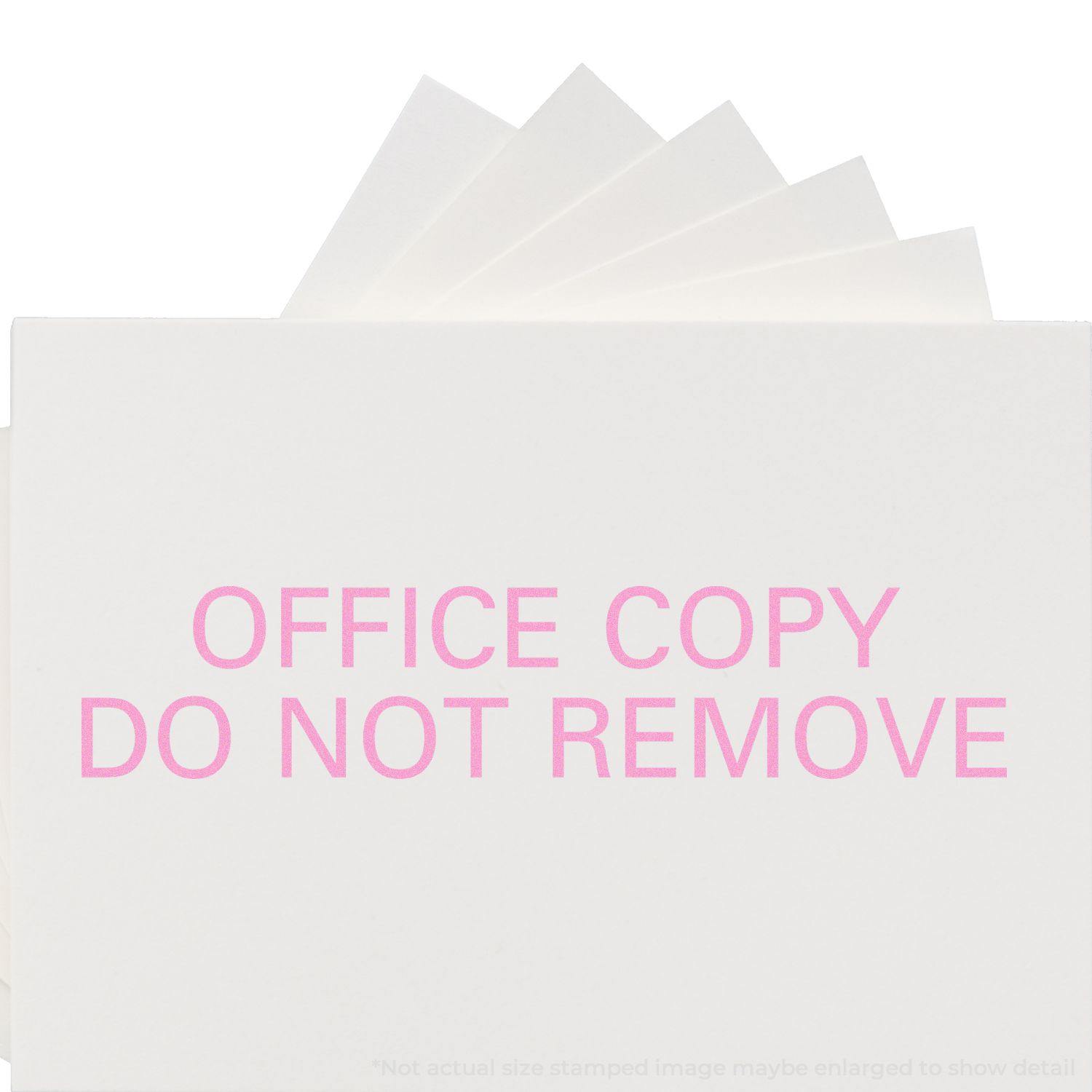 Large Office Copy Do Not Remove Rubber Stamp in use, stamping OFFICE COPY DO NOT REMOVE in pink ink on white paper.