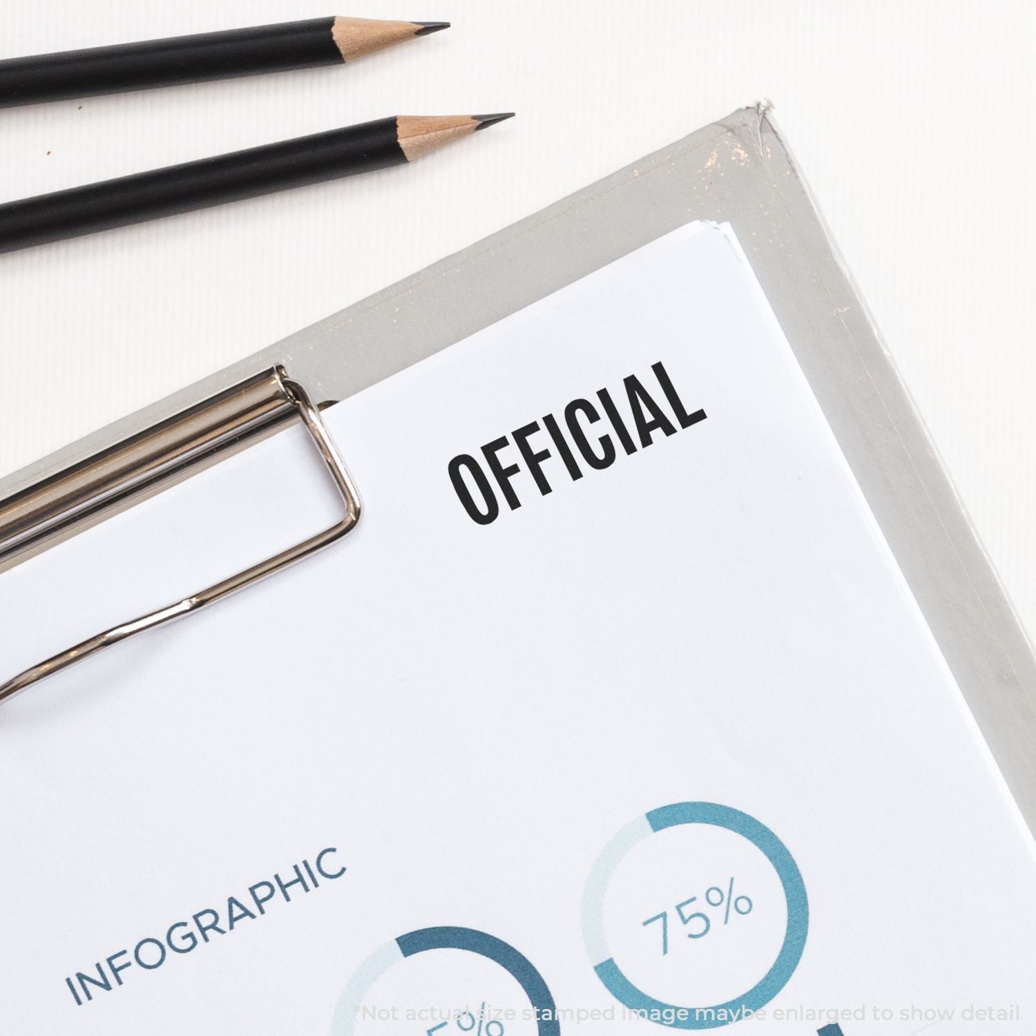 Self Inking Official Stamp marking OFFICIAL on a document beside two black pencils and a clipboard.