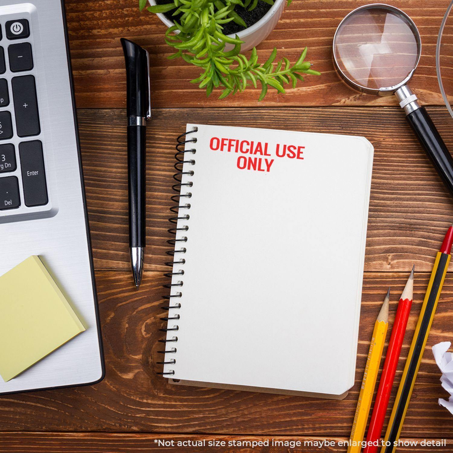 Large Pre-Inked Official Use Only Stamp on a notebook, surrounded by a laptop, pen, sticky notes, magnifying glass, and pencils on a wooden desk.