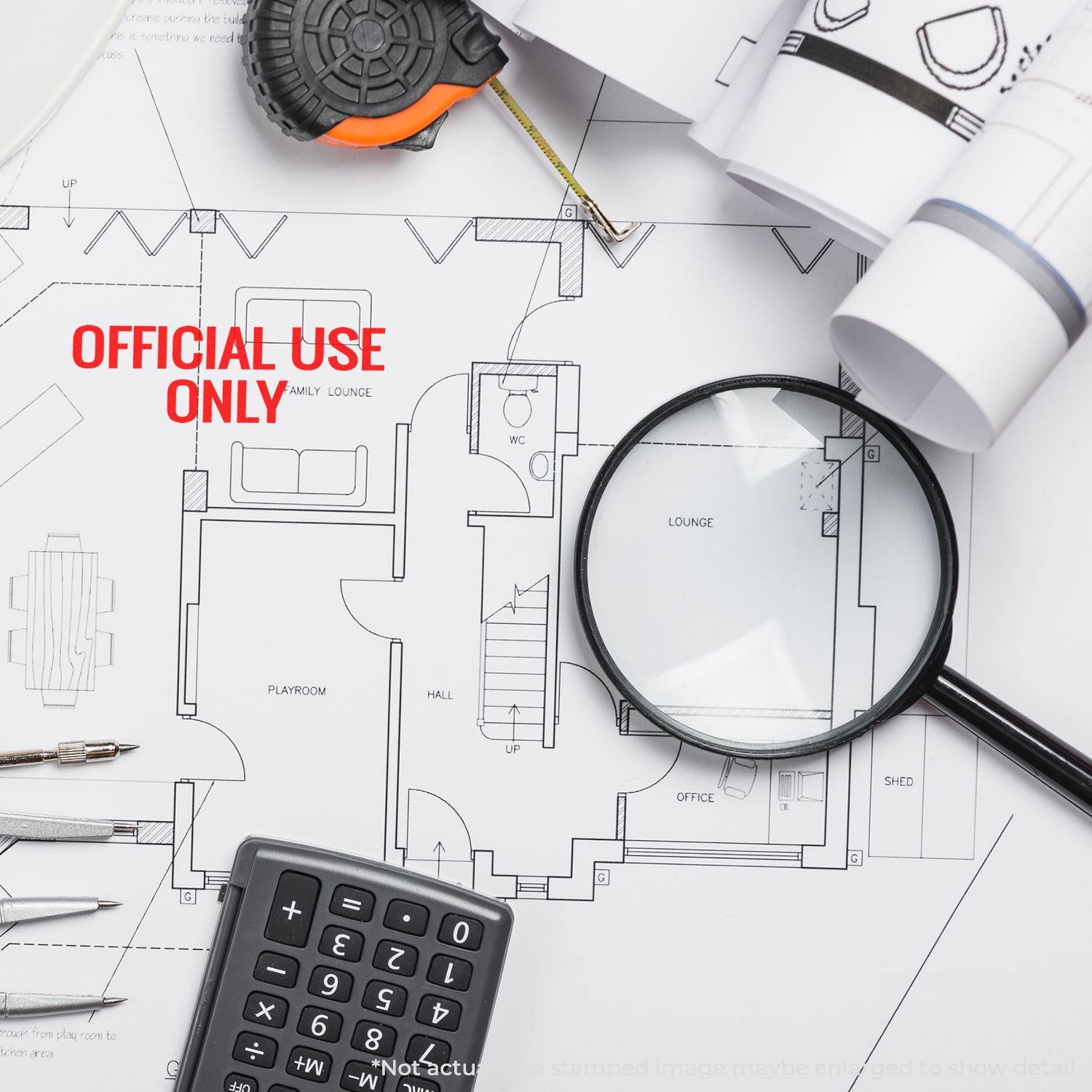 A Large Official Use Only Rubber Stamp marks a floor plan. Nearby are a magnifying glass, calculator, tape measure, and architectural tools.