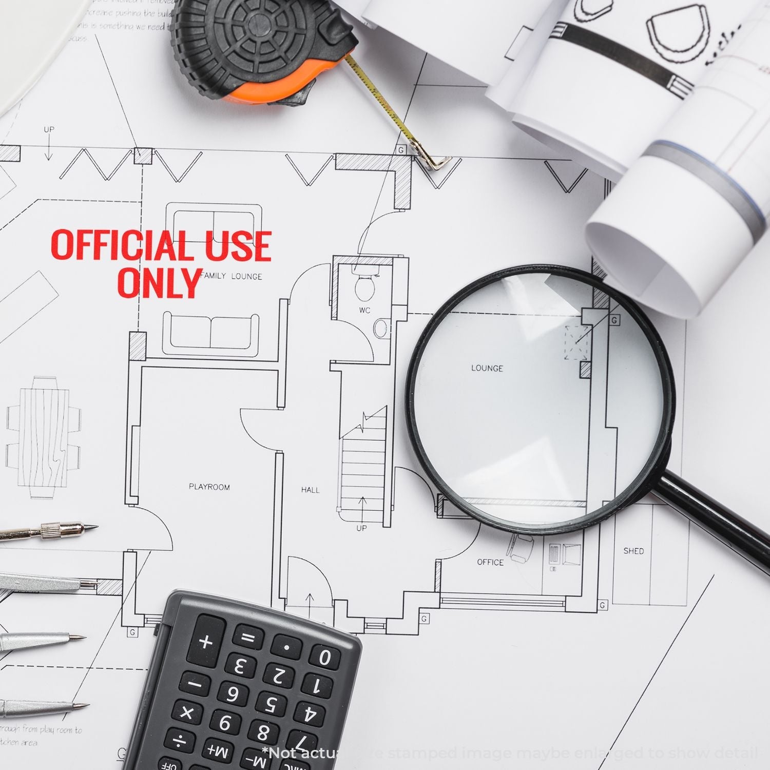 A Self Inking Official Use Only Stamp marks a blueprint, surrounded by a magnifying glass, calculator, tape measure, and pens.