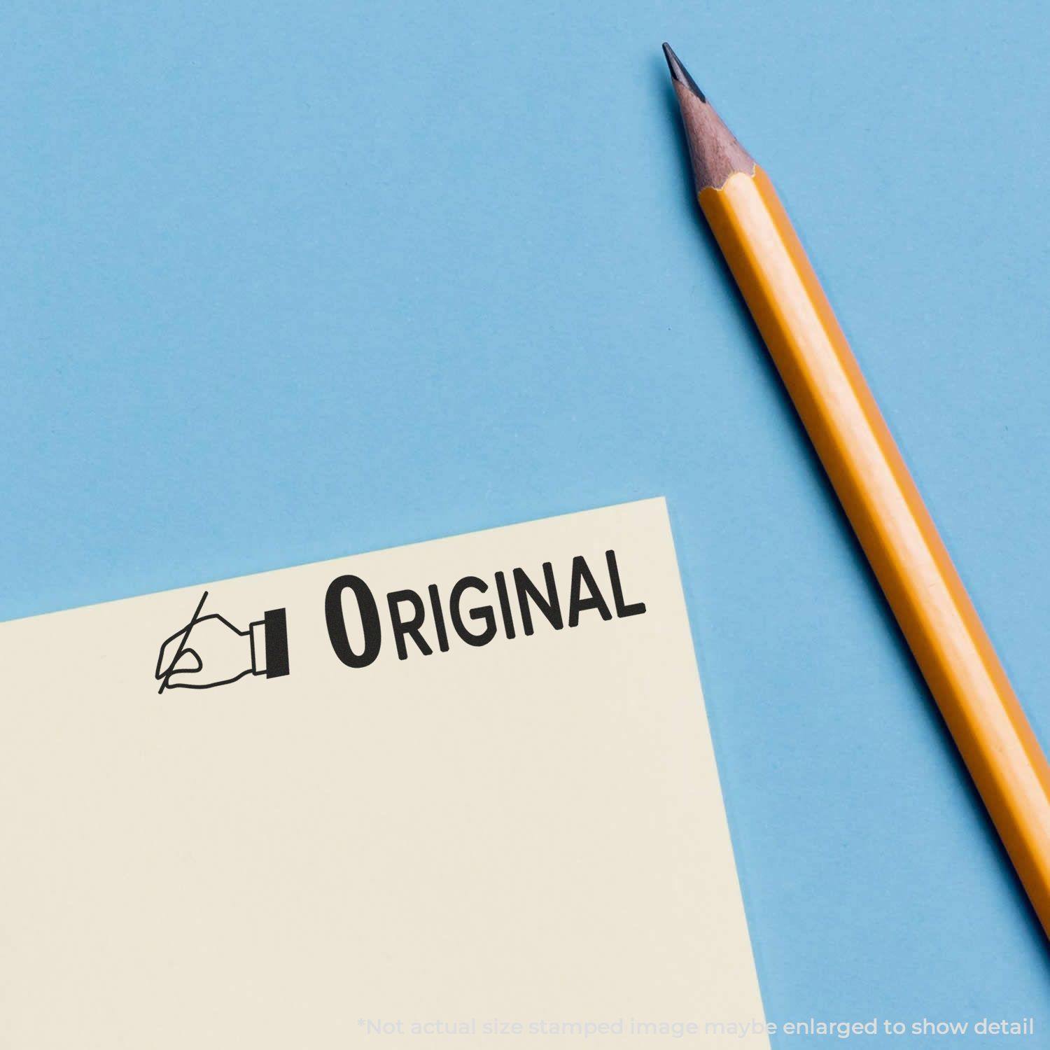 Large Self Inking Original with Hand Stamp imprinting ORIGINAL on a yellow paper next to a sharpened yellow pencil on a blue background.