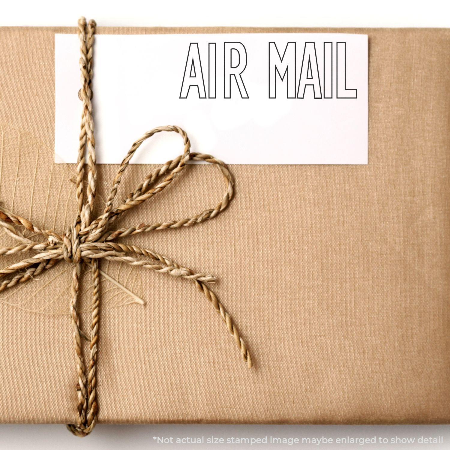 A brown package tied with twine, featuring a Large Outline Air Mail Rubber Stamp on a white label.