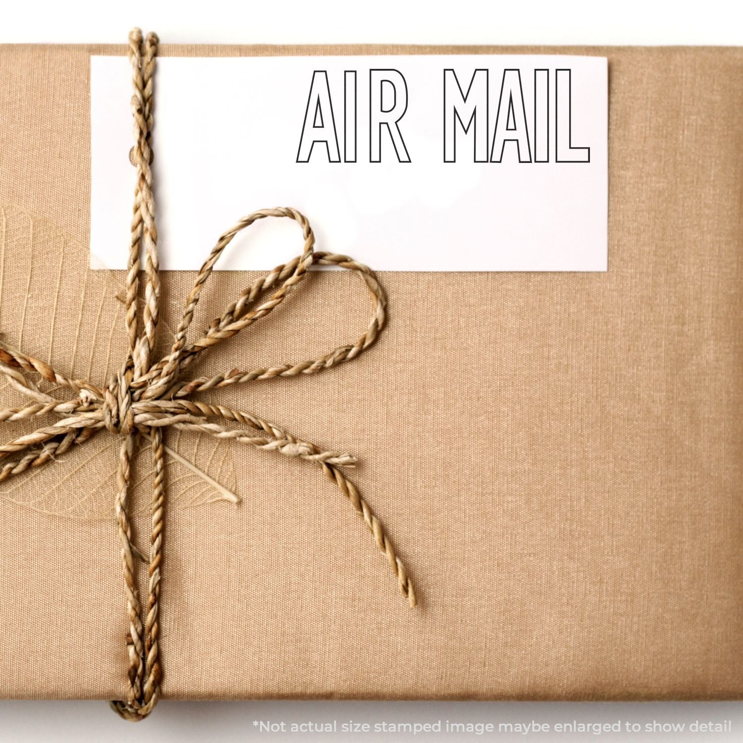 A brown wrapped package with a twine bow and a white label stamped with AIR MAIL using the Self Inking Outline Air Mail Stamp.