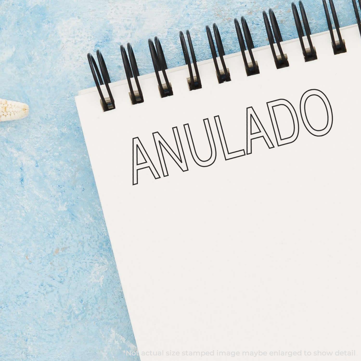 Large Pre-Inked Outline Anulado Stamp used on a white notepad with a blue background.