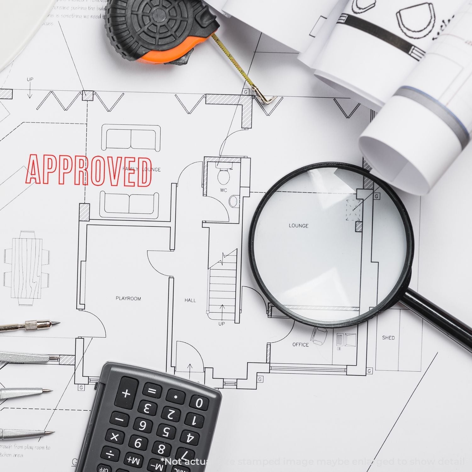 Self Inking Outline Approved Stamp on architectural blueprints with a magnifying glass, calculator, and measuring tape nearby.