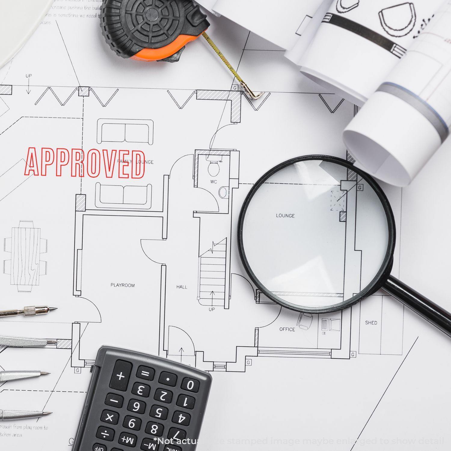 Architectural blueprint with 'Approved' marked using a Slim Pre-Inked Outline Approved Stamp, surrounded by tools and a magnifying glass.