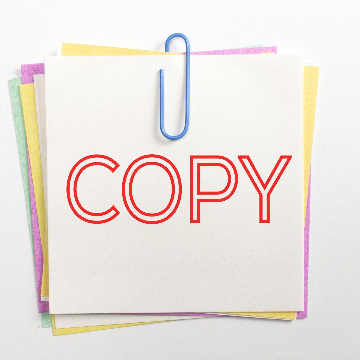 Sticky notes stamped with 'COPY' in red ink using a Slim Pre-Inked Outline Copy Stamp, held together by a blue paperclip.