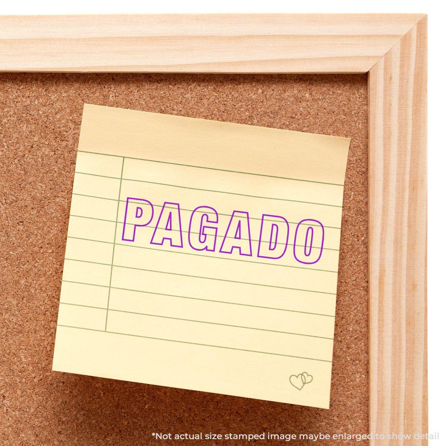 Large Pre-Inked Outline Pagado Stamp used on a yellow sticky note pinned to a corkboard, displaying the word PAGADO in purple ink.