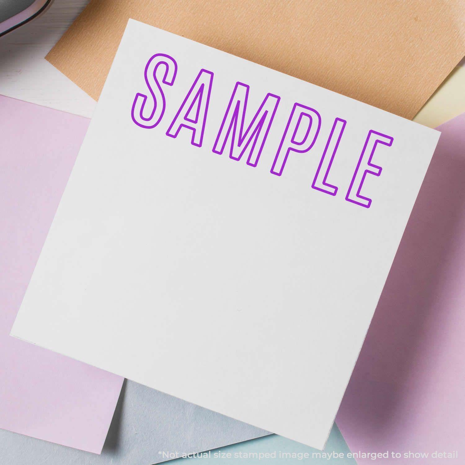 Large Outline Sample Rubber Stamp in purple ink on white paper, surrounded by pastel-colored papers.