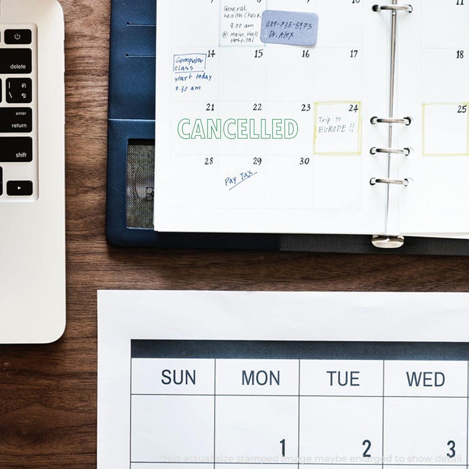 Large Pre-Inked Cancelled Stamp used on a calendar page, placed on a wooden desk next to a laptop and another calendar sheet.