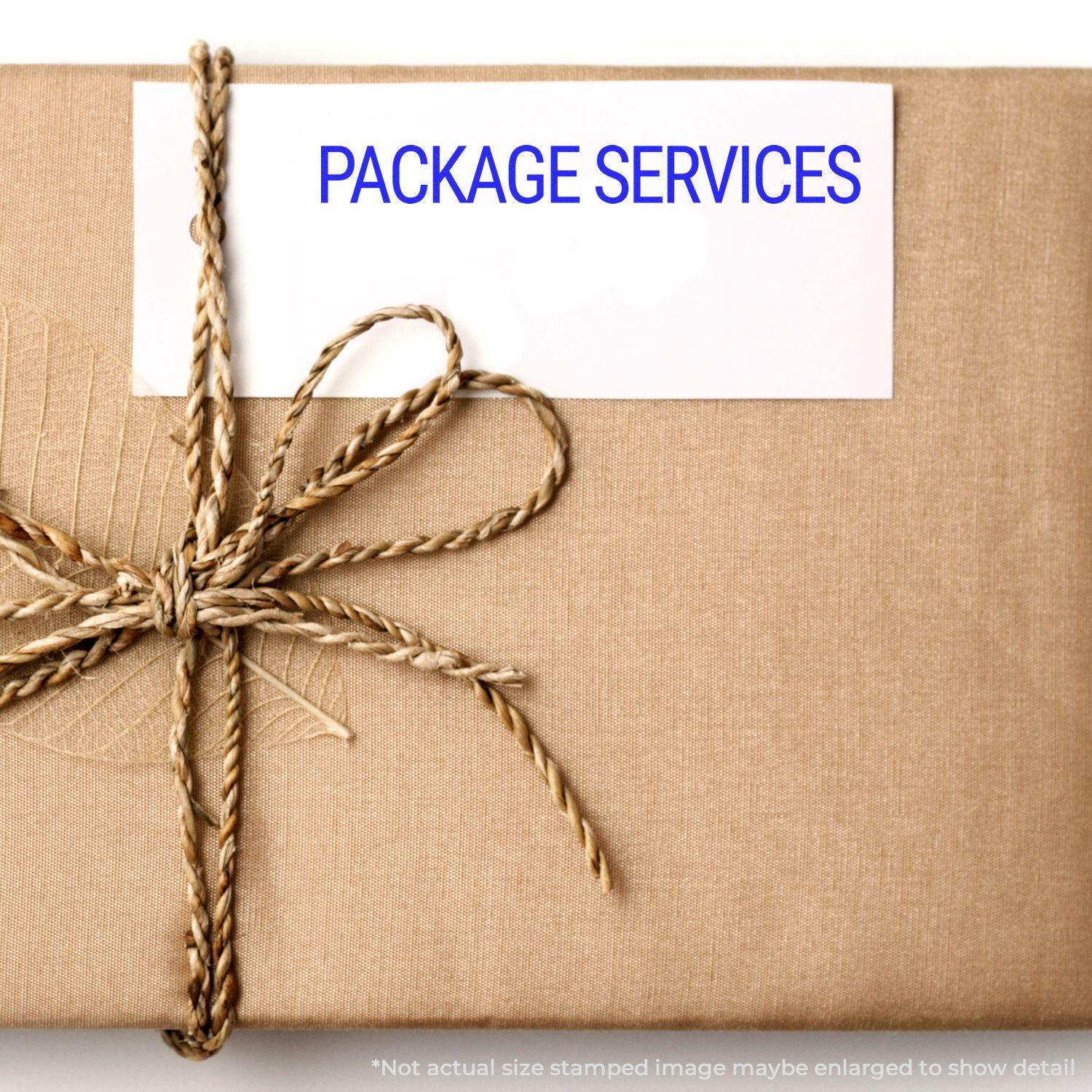 A brown package with a twine bow and a white card stamped with PACKAGE SERVICES using the Large Pre-Inked Package Services Stamp.