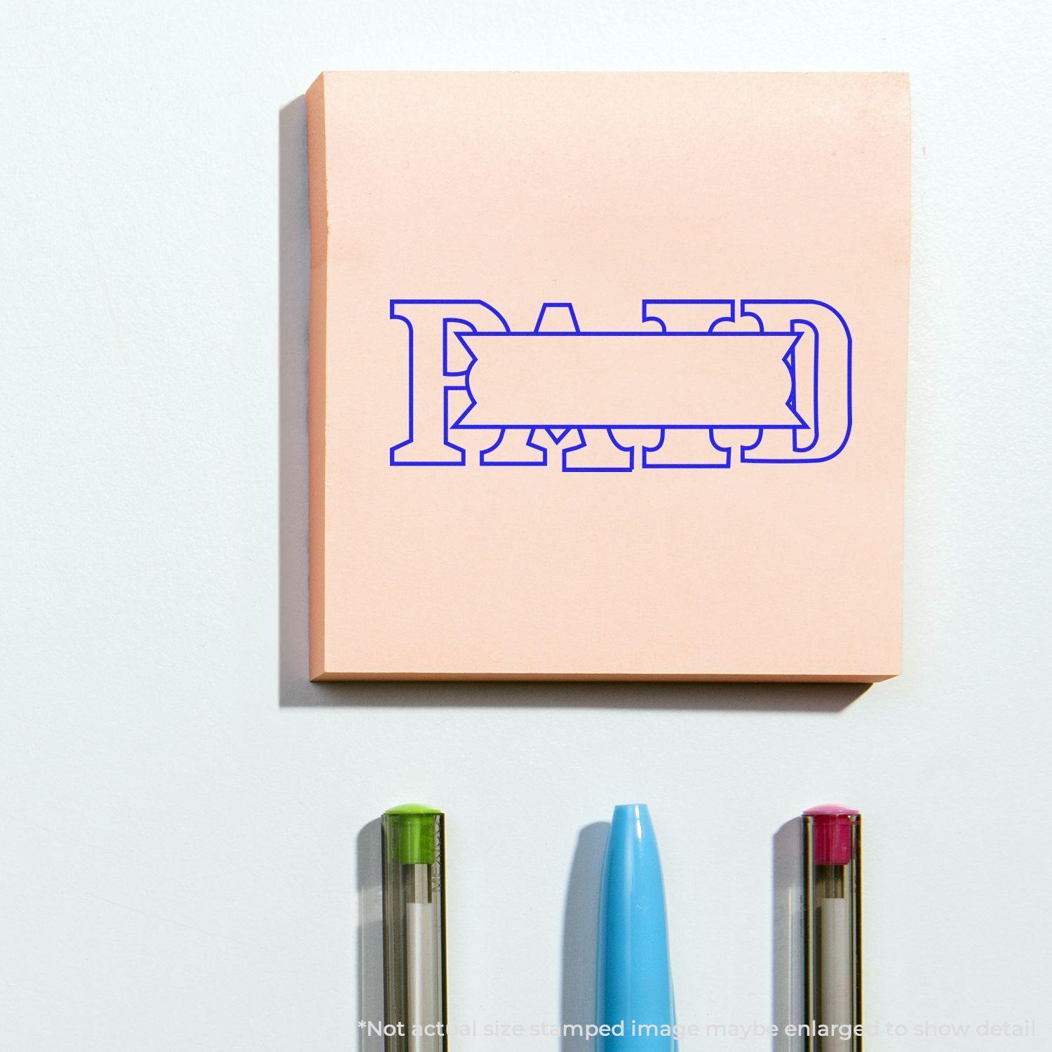 Large Paid with Box Rubber Stamp imprint on a pink sticky note, with three pens below.