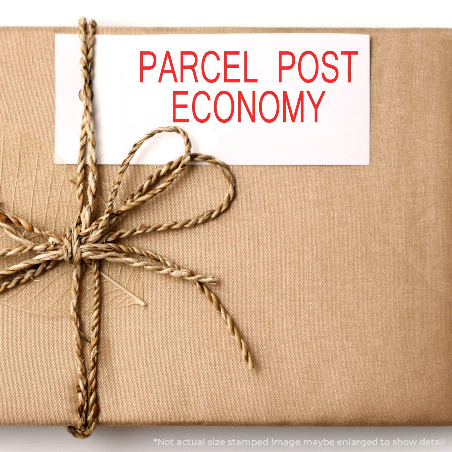 A brown parcel with a twine bow and a Large Parcel Post Economy Rubber Stamp mark in red on a white label.