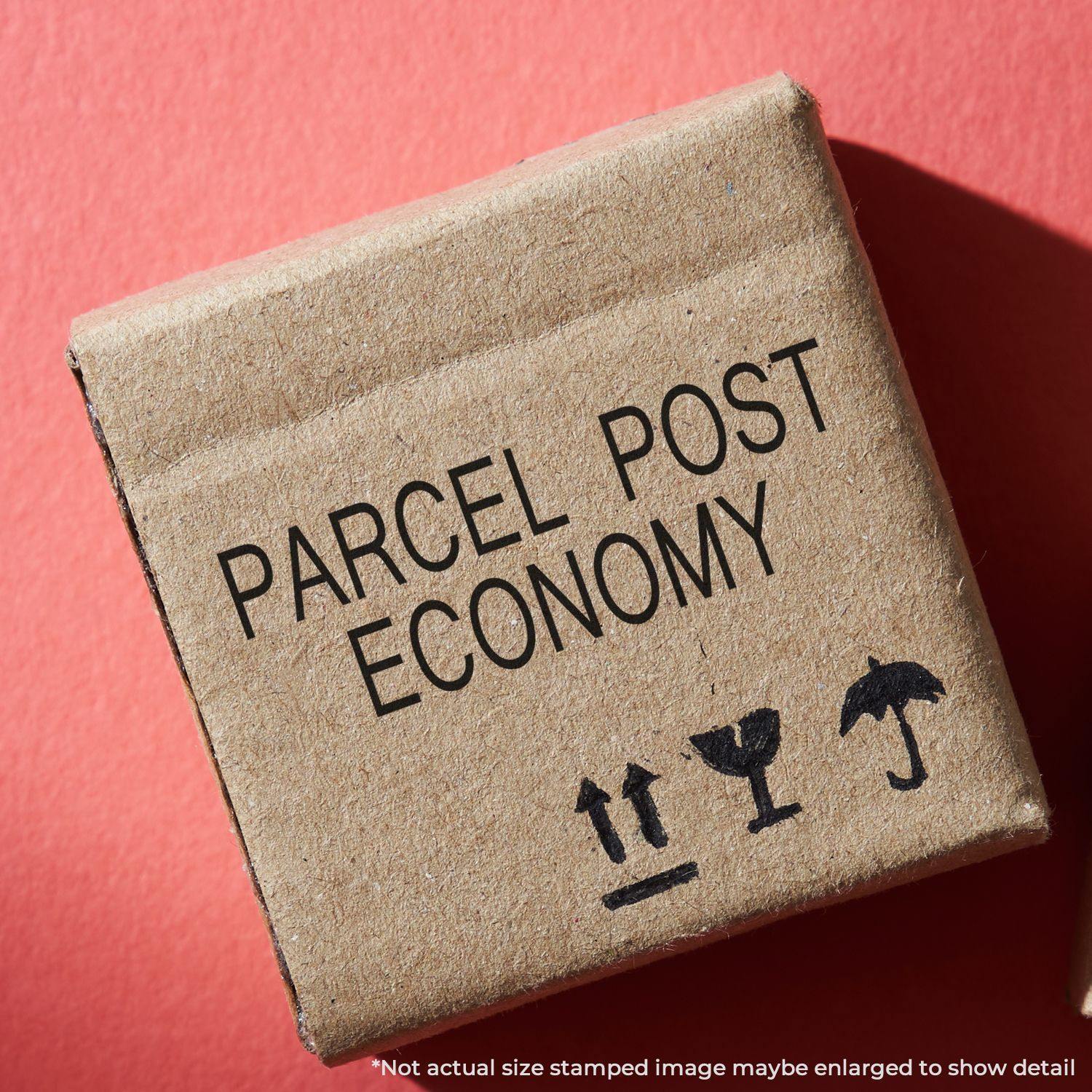 Parcel Post Economy rubber stamp on a brown cardboard box with shipping symbols on a red background.