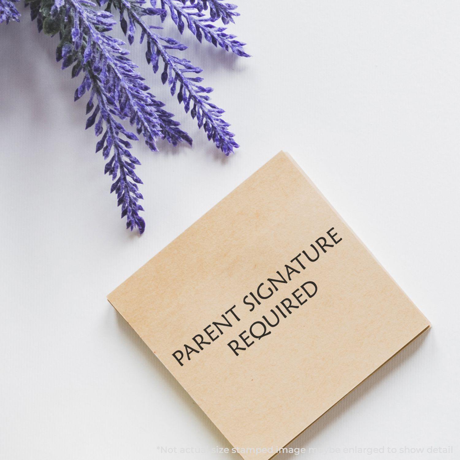 Parent Signature Required Rubber Stamp on a white surface with purple flowers in the corner, emphasizing the stamp text.