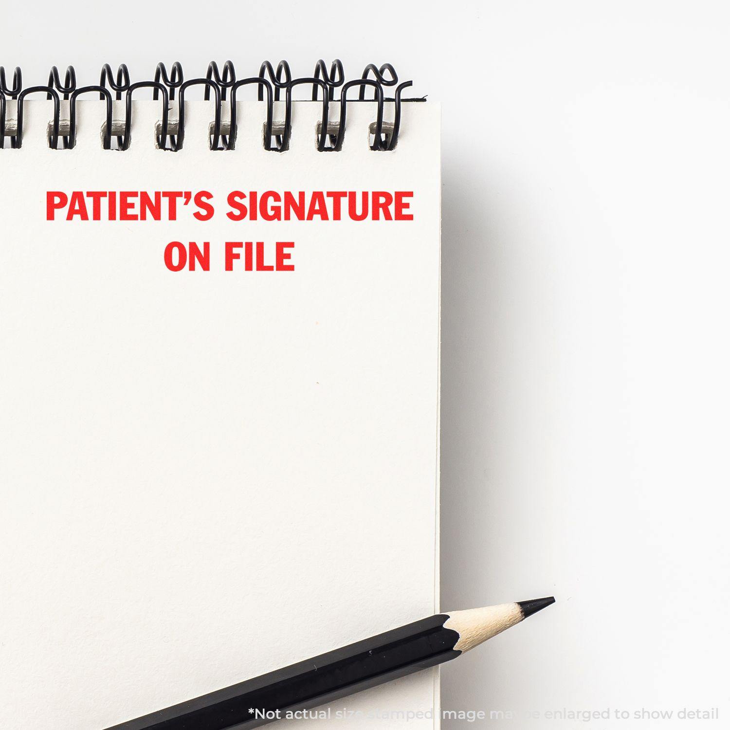 A Large Self Inking Patient's Signature on File Stamp imprint in red ink on a white notepad, with a black pencil placed beside it.