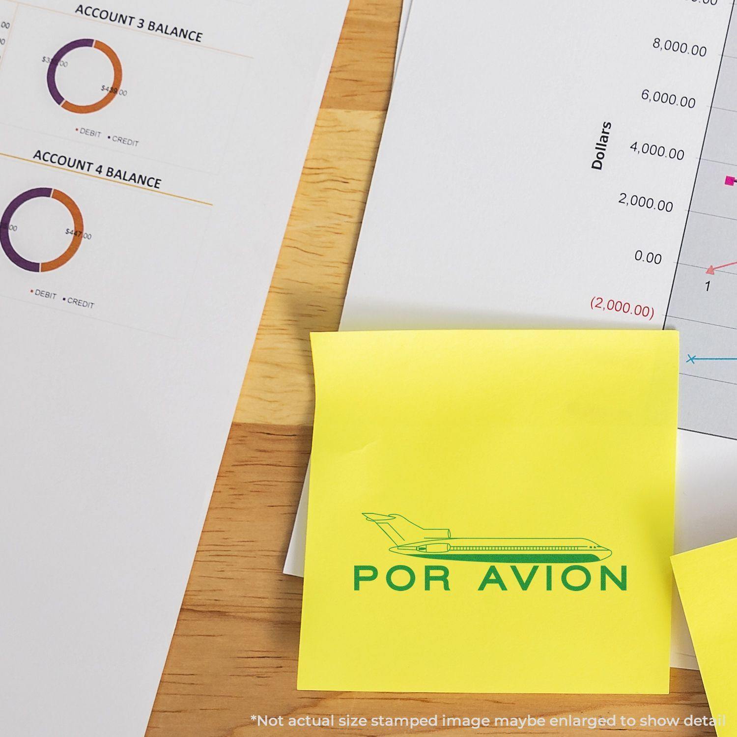 Large Pre-Inked Por Avion Stamp on a yellow sticky note, surrounded by financial documents and charts on a wooden desk.