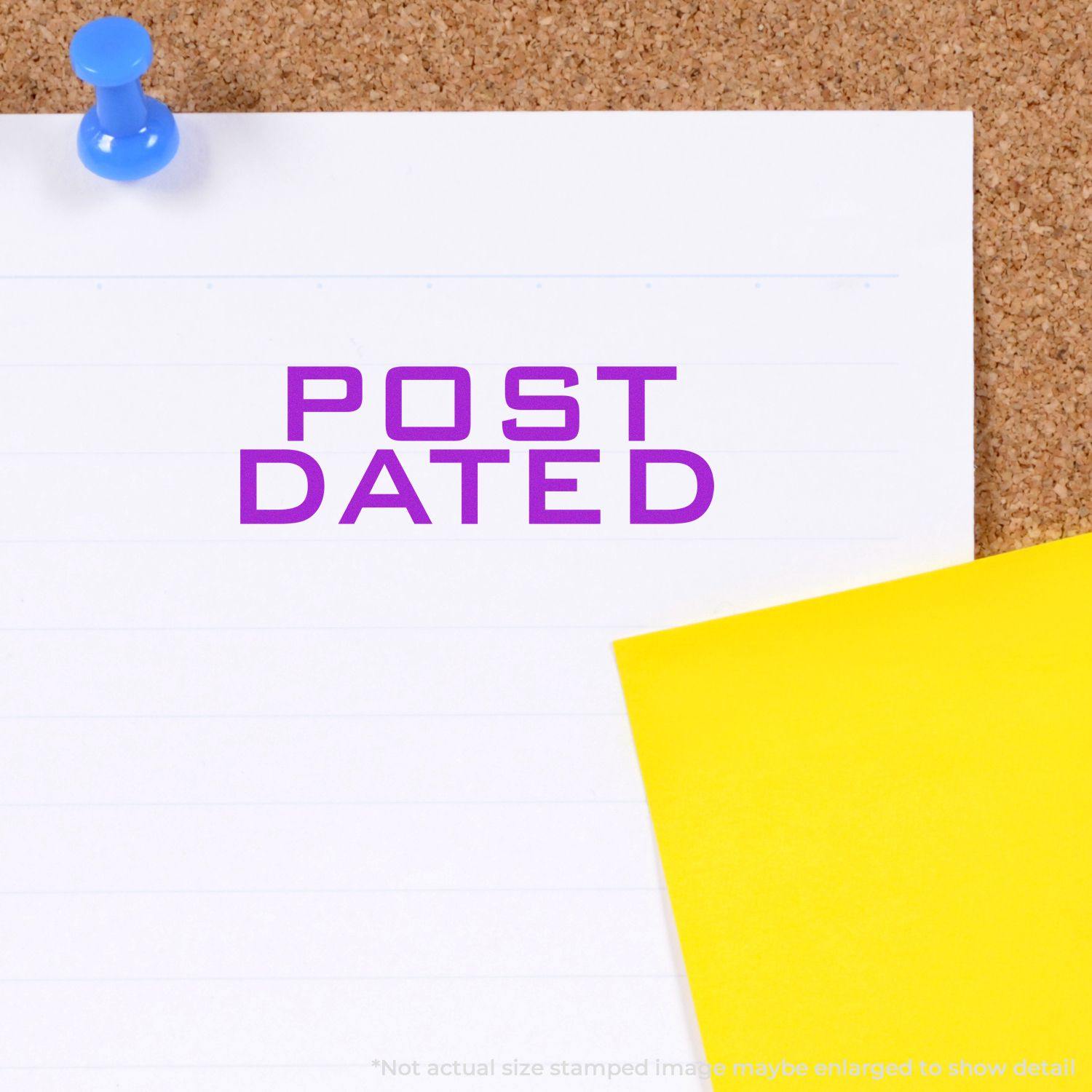 Large Post Dated Rubber Stamp in purple ink on white paper pinned to a corkboard with a blue pushpin and a yellow sticky note.