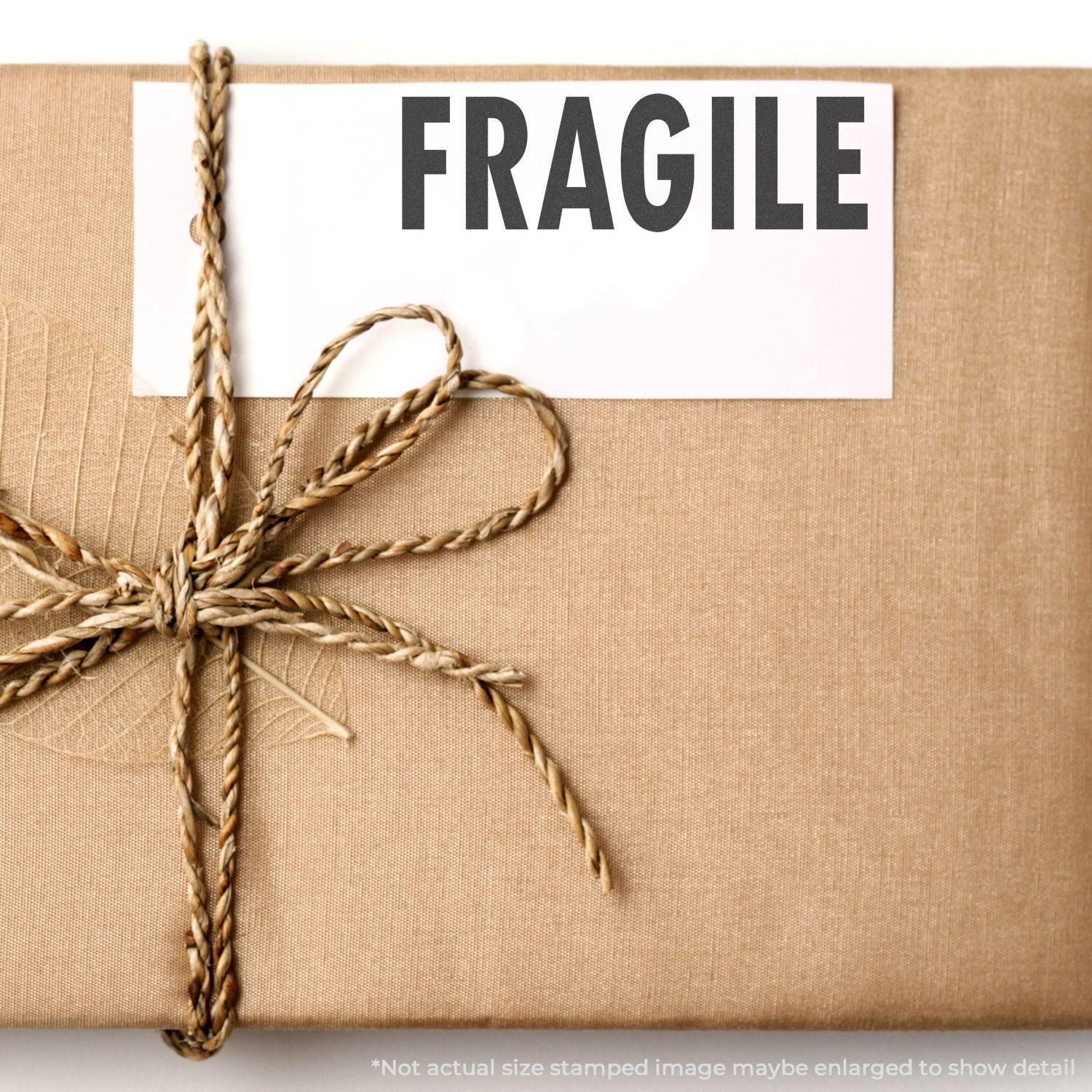 A package wrapped in brown paper with a twine bow, stamped with FRAGILE using the Large Fragile Rubber Stamp.