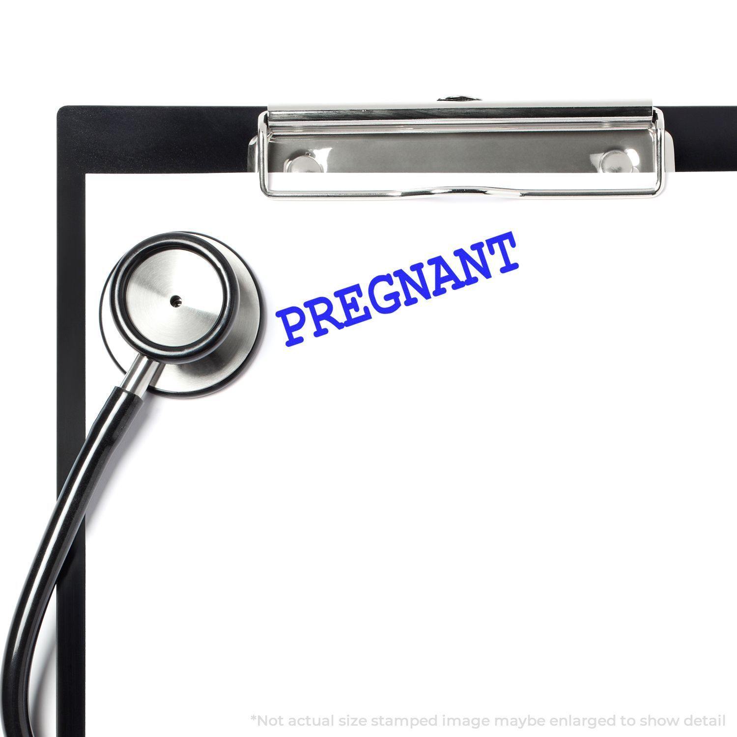 A clipboard with a stethoscope and a blue Pregnant rubber stamp impression on a white sheet of paper.