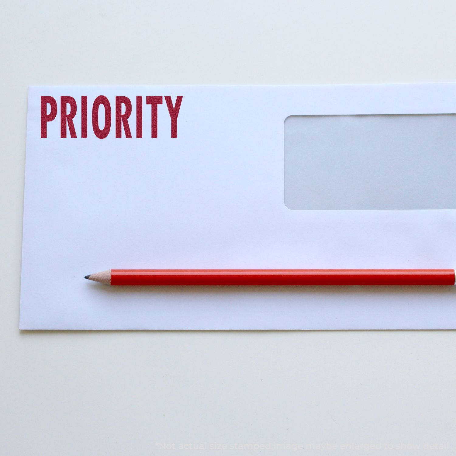 Self Inking Priority Mailing Stamp marking PRIORITY in red on a white envelope with a red pencil placed diagonally across the envelope.