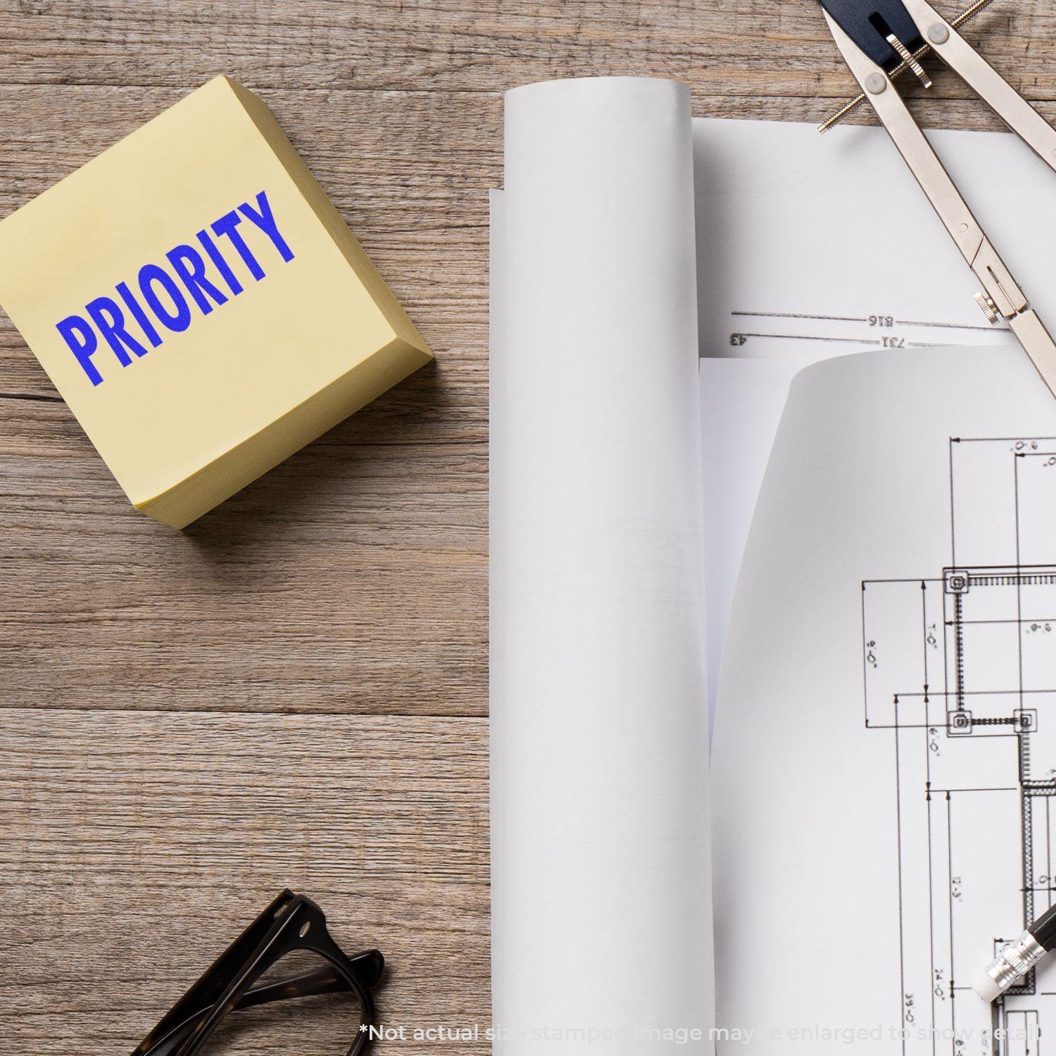 Large Pre-Inked Priority Stamp in use on a desk with architectural plans, a compass, and glasses.