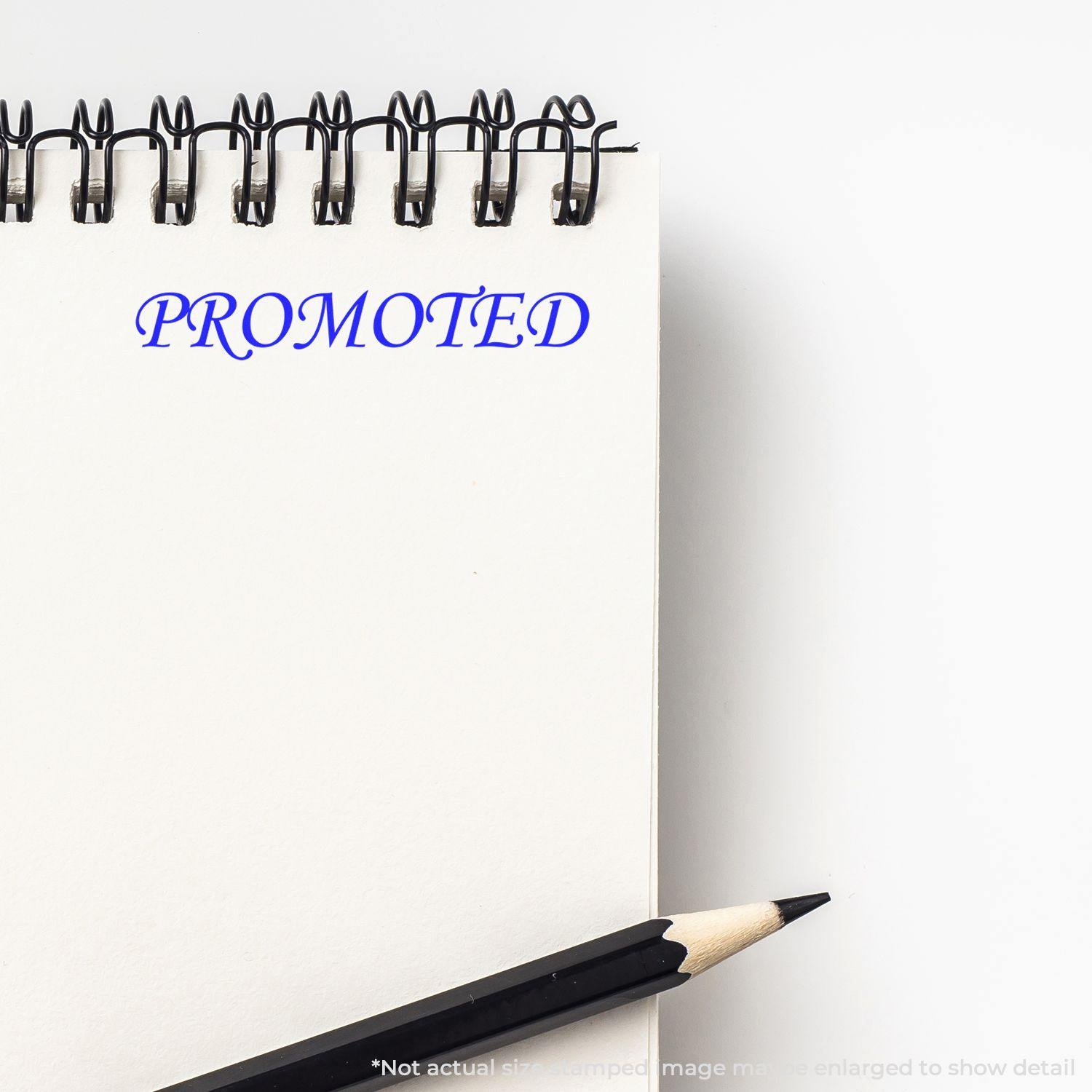 Slim Pre-Inked Promoted Stamp imprint on a white notepad with a black pencil beside it.