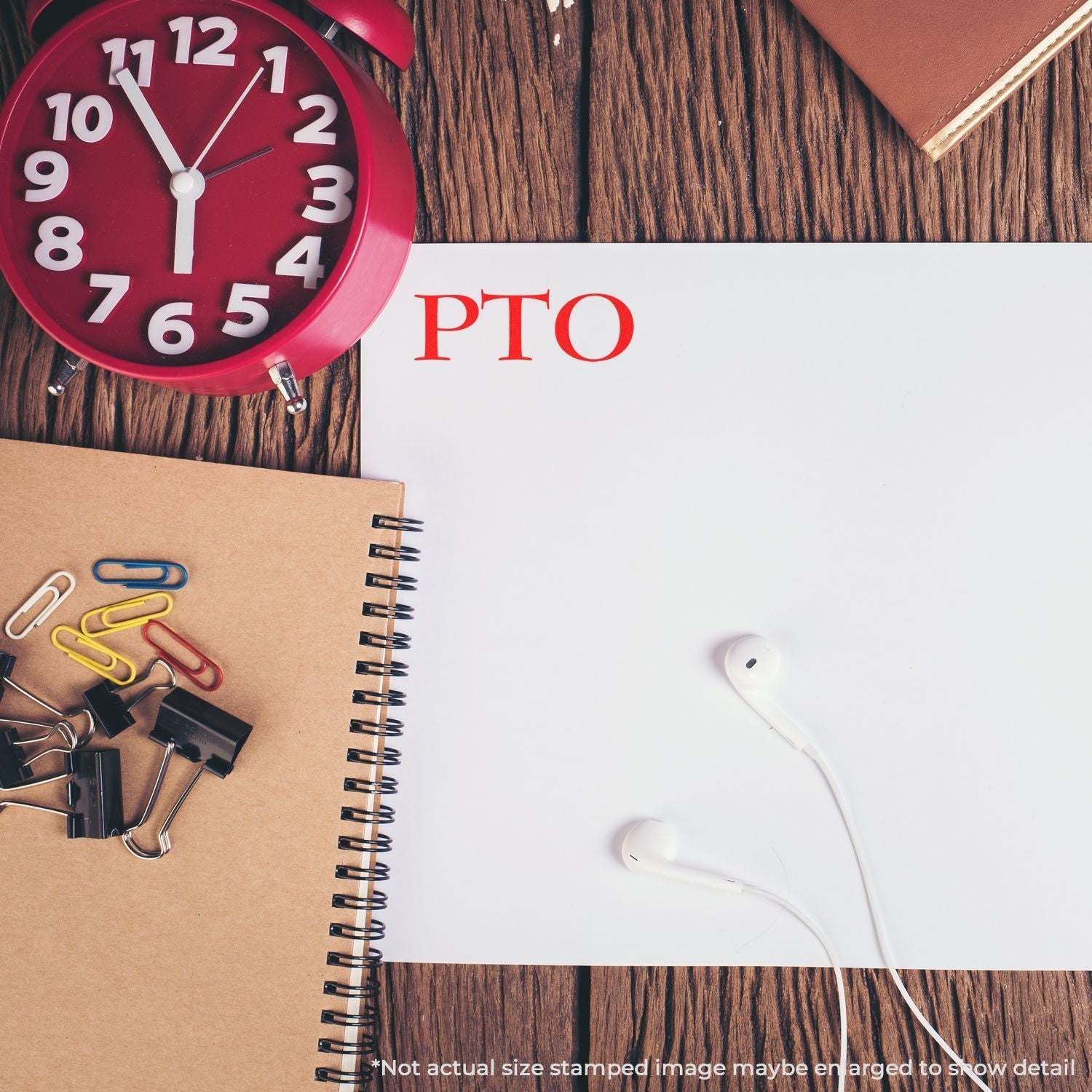 Desk with red clock, notebooks, paper clips, and earphones. PTO stamped in red using Self Inking PTO Stamp on white paper.