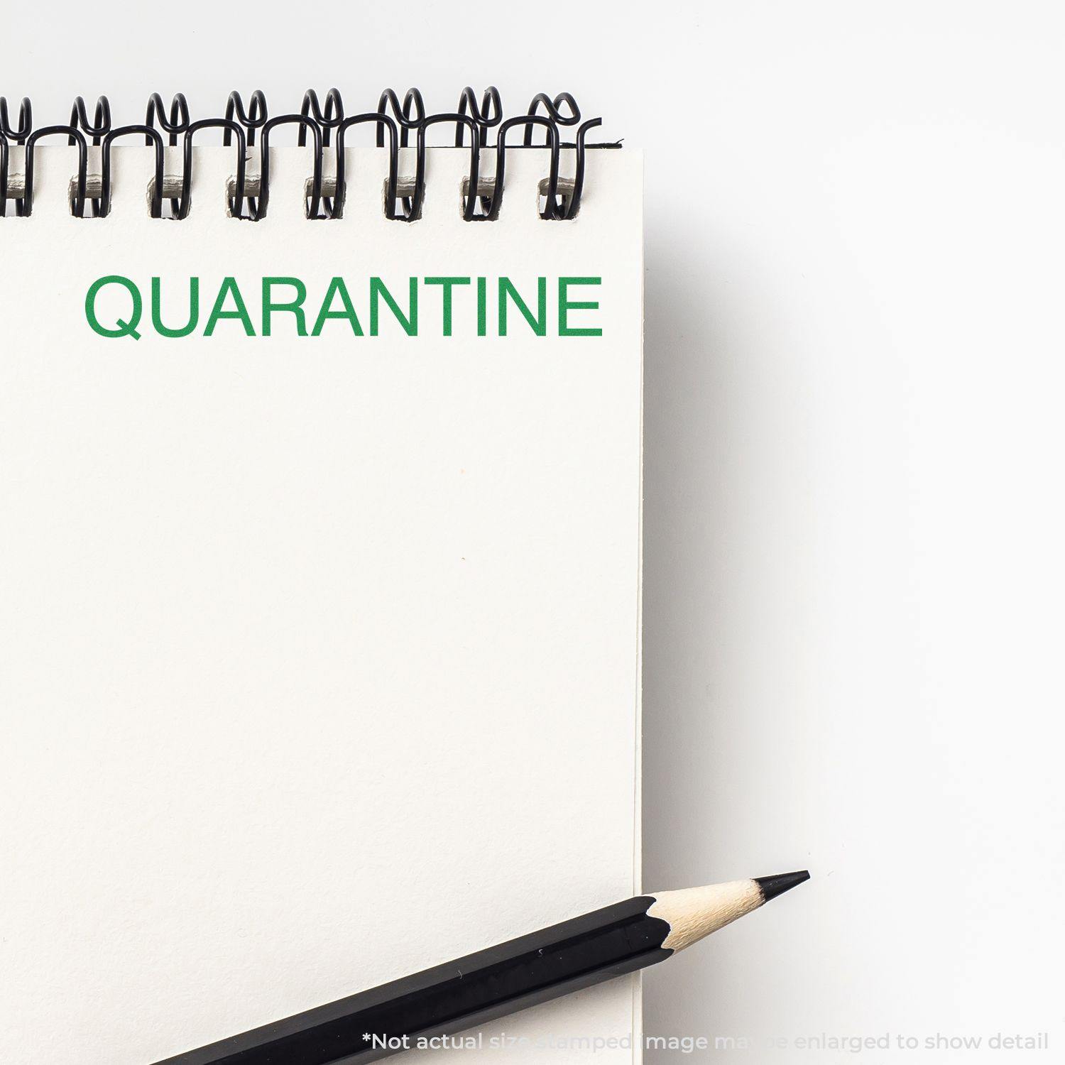 A notepad with "QUARANTINE" stamped in green using the Quarantine Rubber Stamp, with a pencil placed beside the notepad.