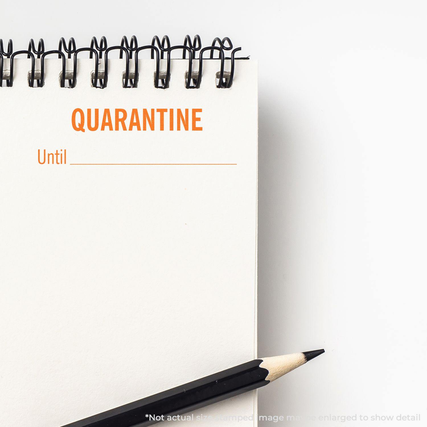 Large Pre-Inked Quarantine Until Stamp in use on a spiral notebook with a pencil beside it. The stamp reads QUARANTINE Until _______ .