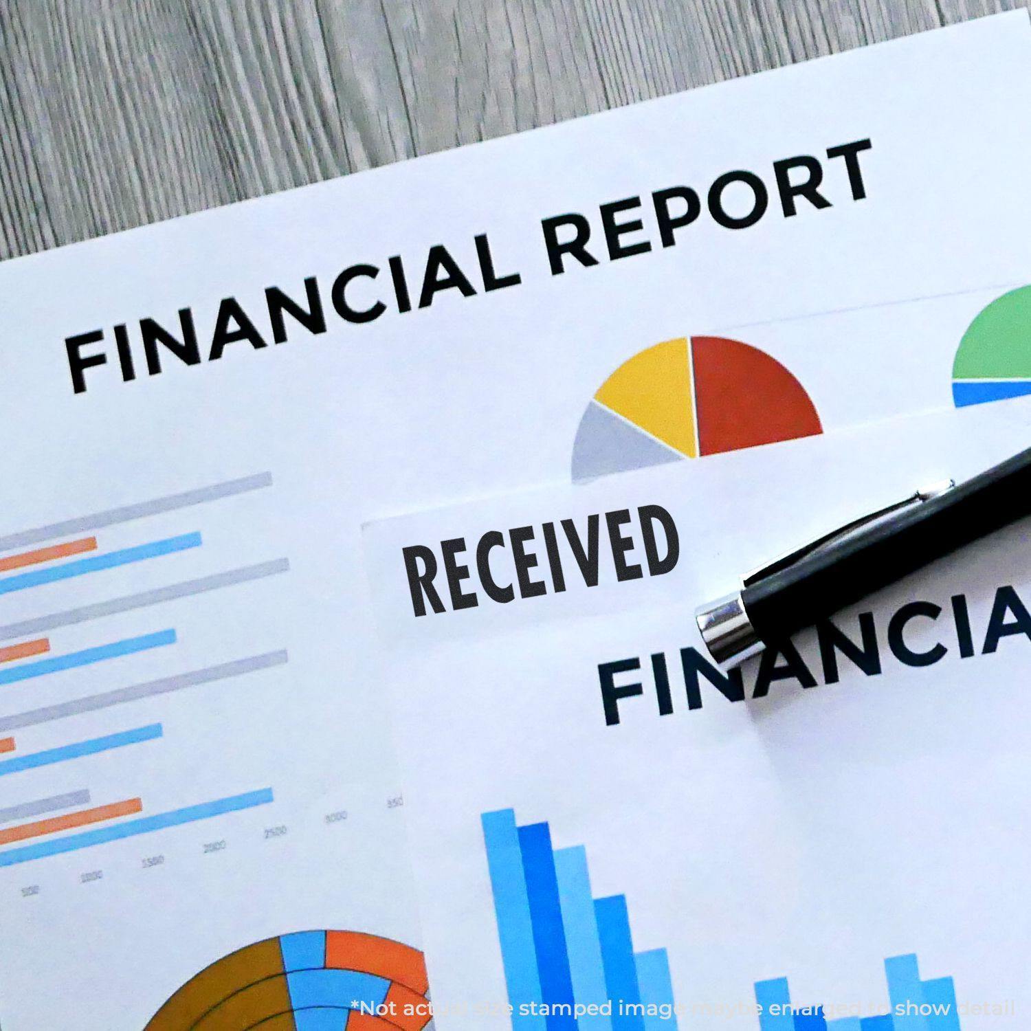 Financial reports stamped with Received using the Large Received Self-Inking Stamp, alongside a pen on a wooden desk.