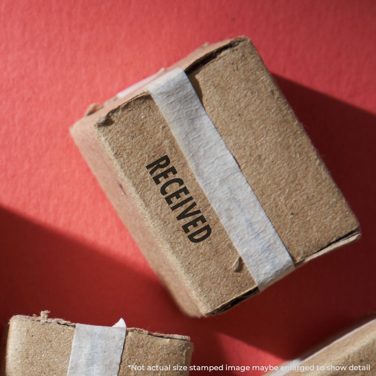 Cardboard box stamped with RECEIVED using the Self Inking Received Stamp, placed on a red surface.