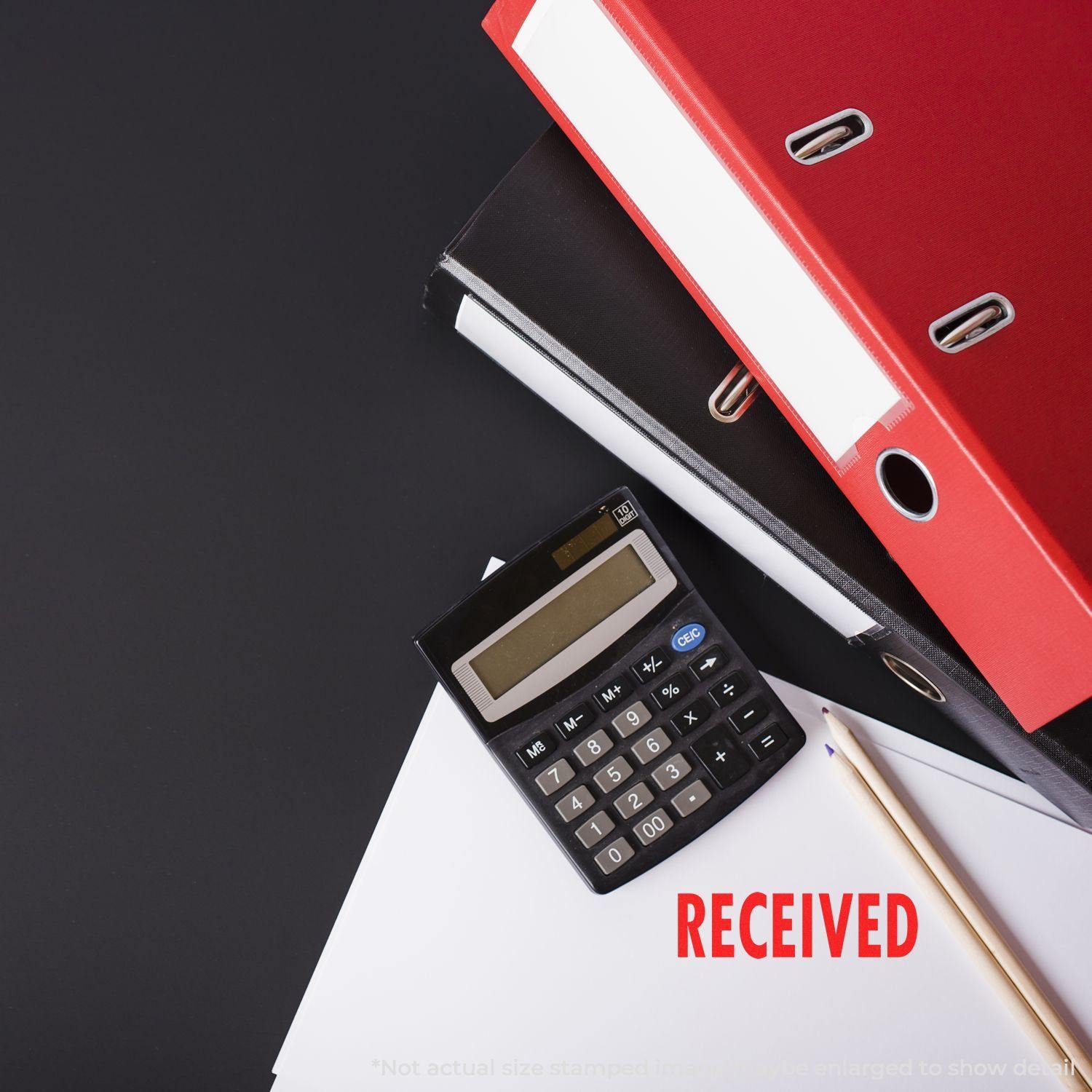 Large Pre-Inked Received Stamp marking RECEIVED in red on paper, next to a calculator, pencil, and stacked binders.