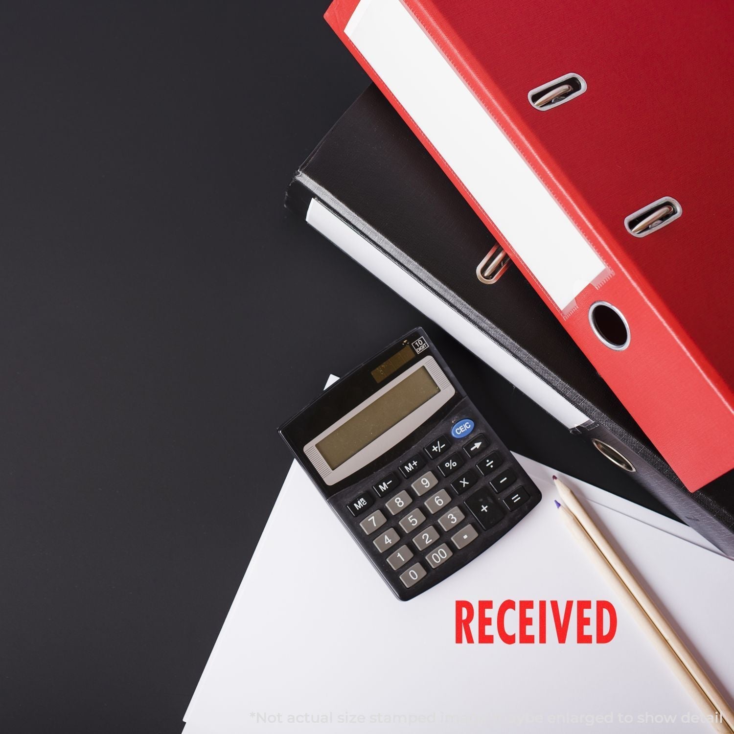 Self Inking Received Stamp used on a document next to a calculator, pencil, and stack of red and black binders.