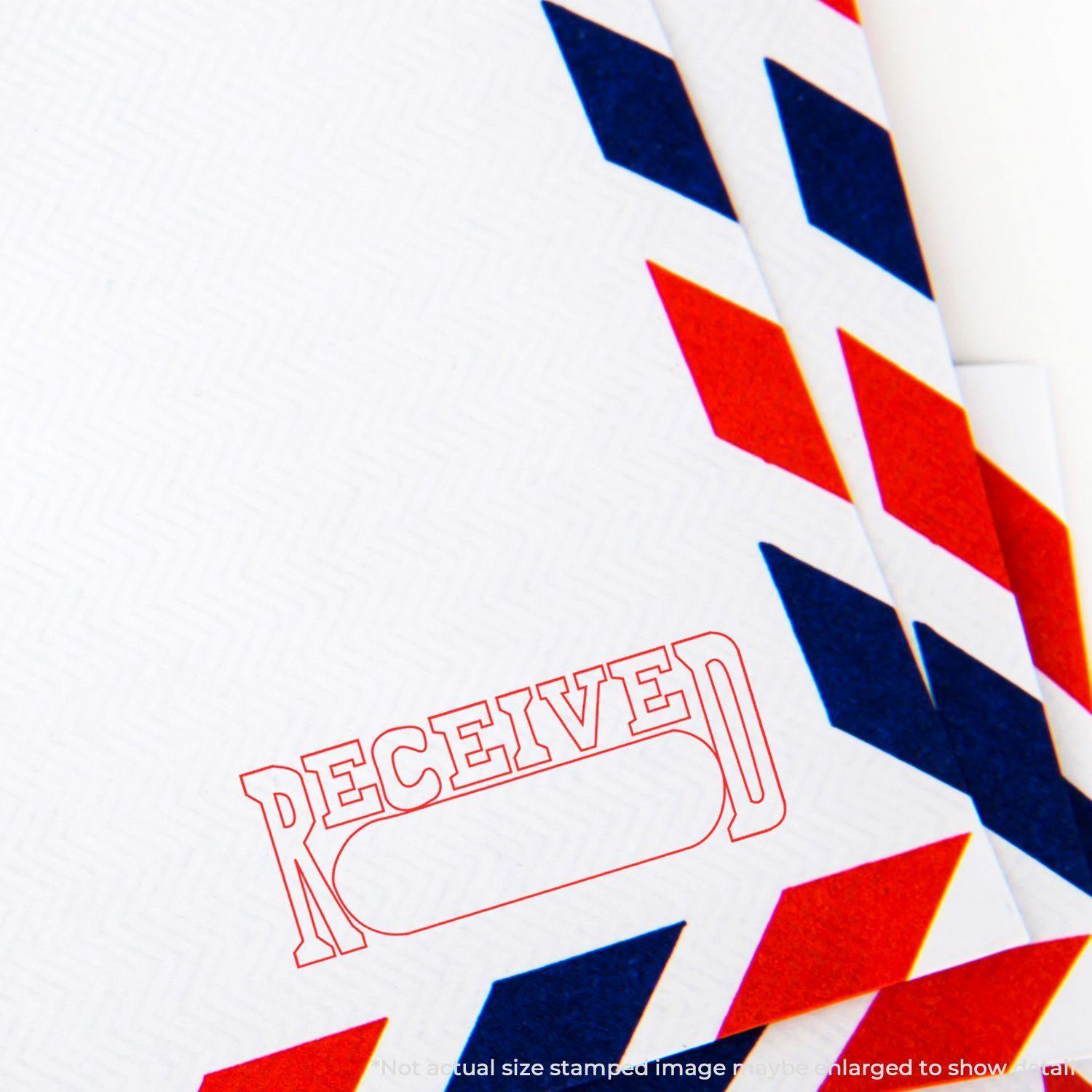 Slim Pre-Inked Received with Date Box Stamp in red ink on a white envelope with red and blue border design.