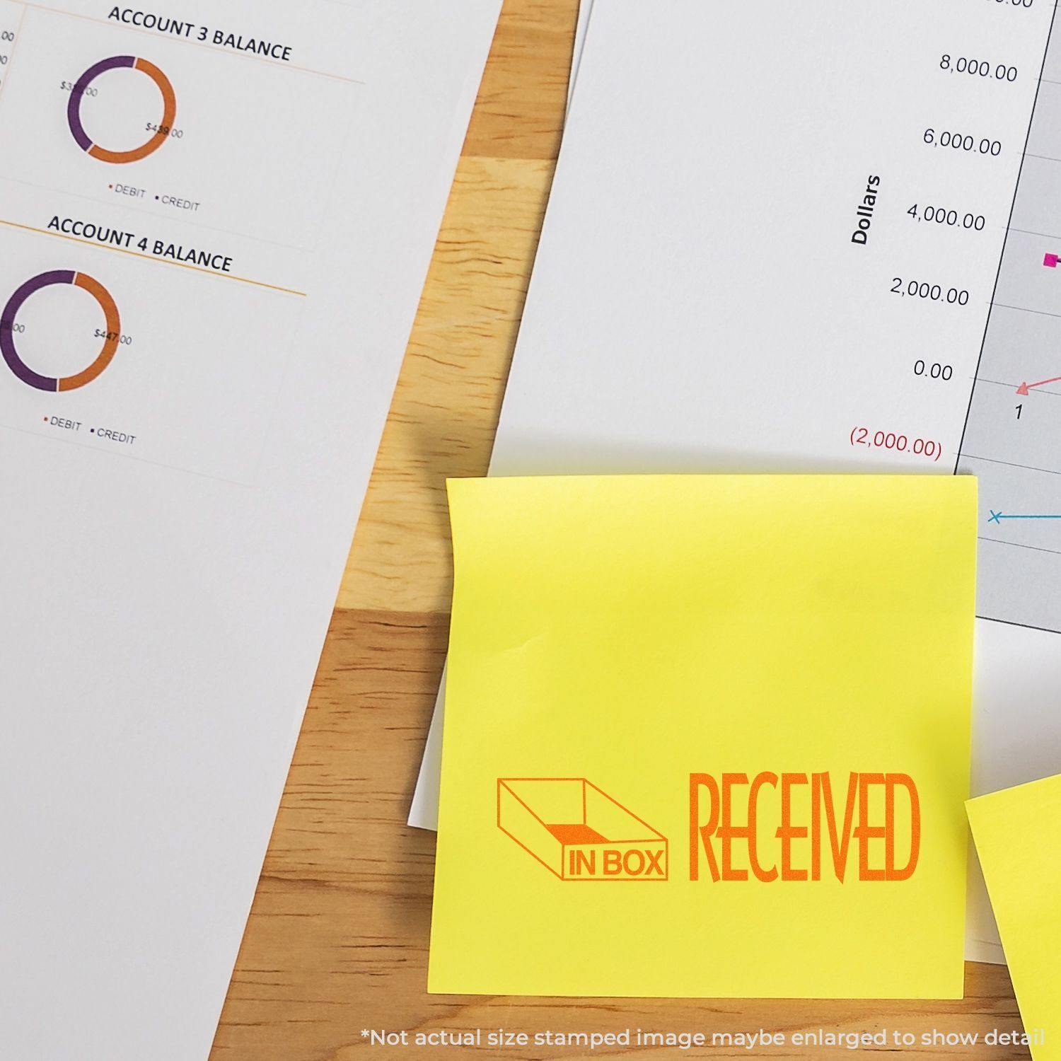 Large Self Inking Received with In Box Icon Stamp used on a yellow sticky note, placed on a desk with financial documents.